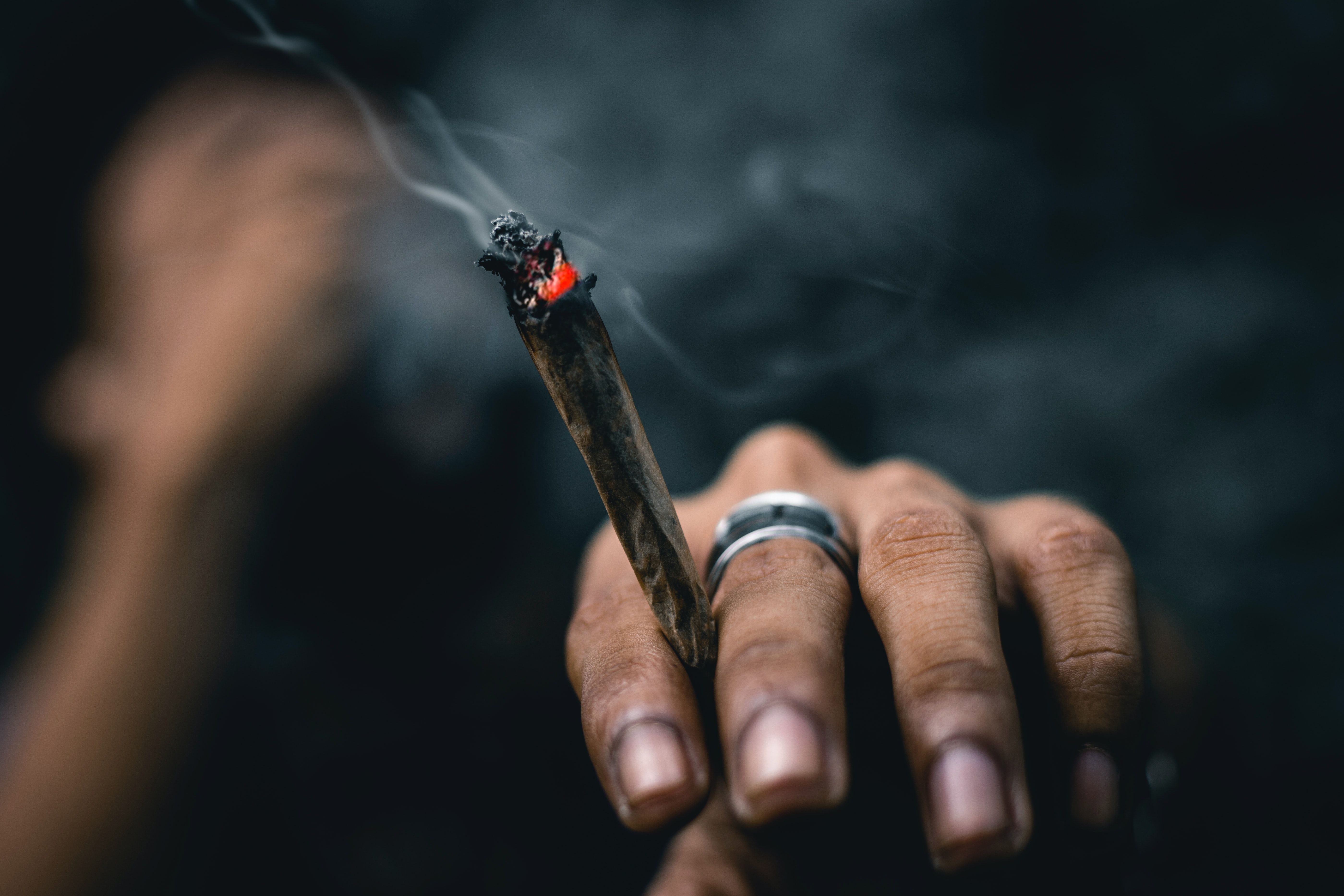 person wearing ring and holding blunt photo