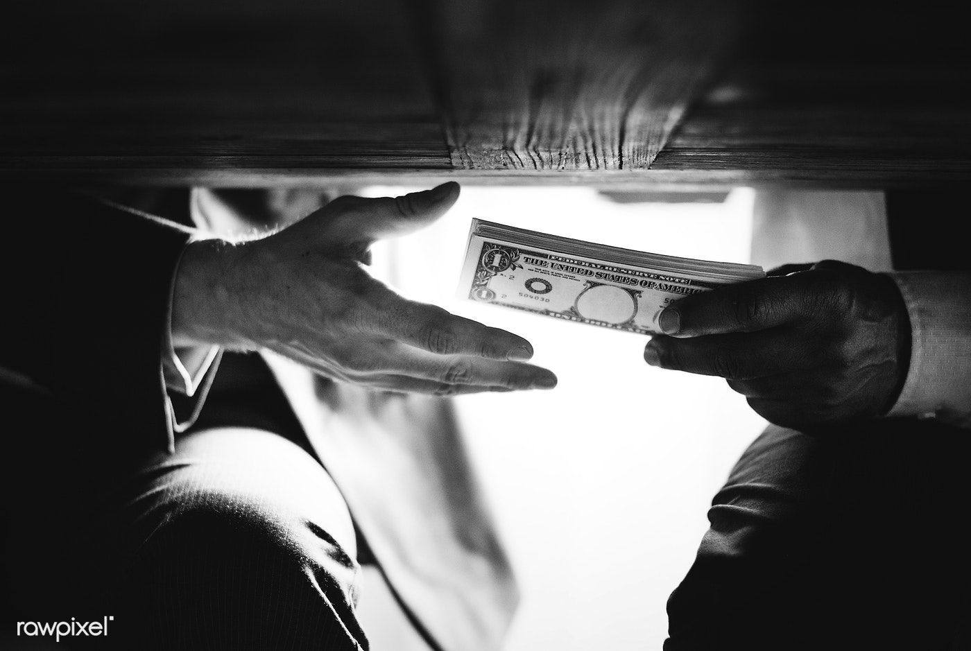 Hands passing money under the table corruption and bribery. free