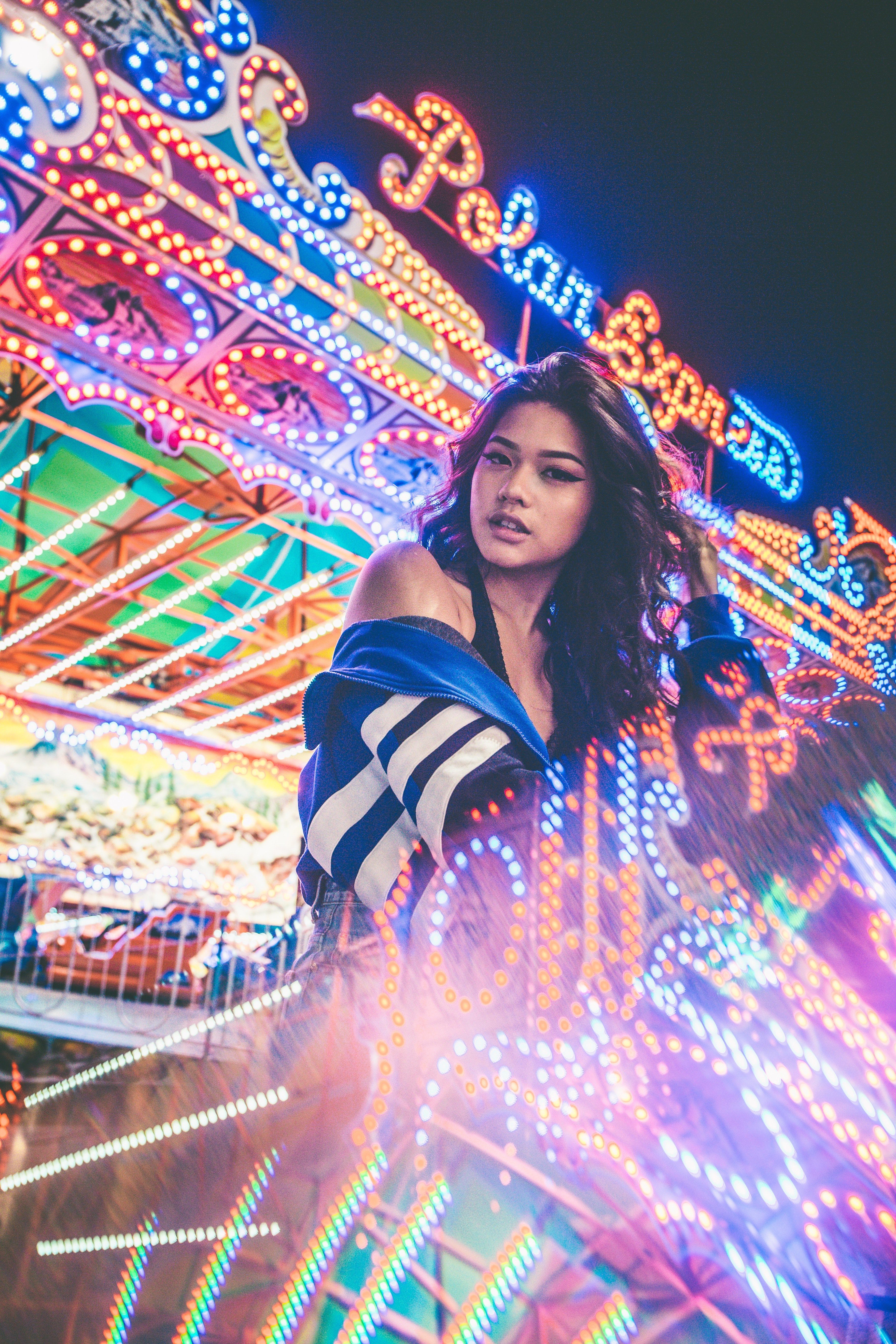 a woman stands among bright neon lights at a carnival