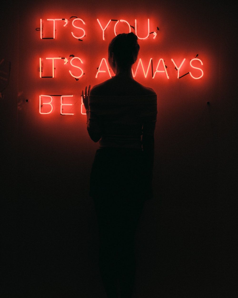 silhouette of woman standing in front of red neon signage low