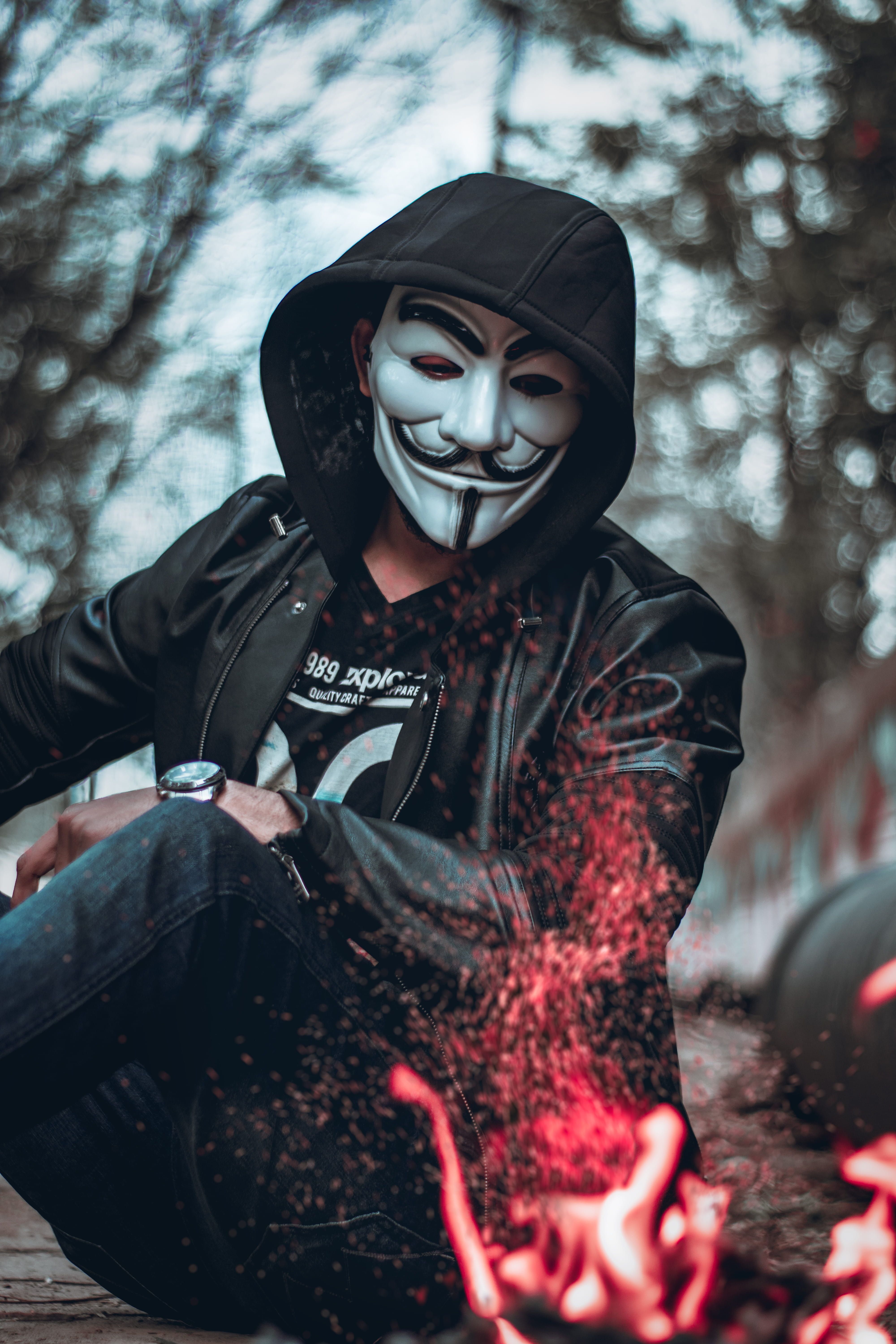 Person Wearing Guys Fawkes Mask Watching Flame blurred background