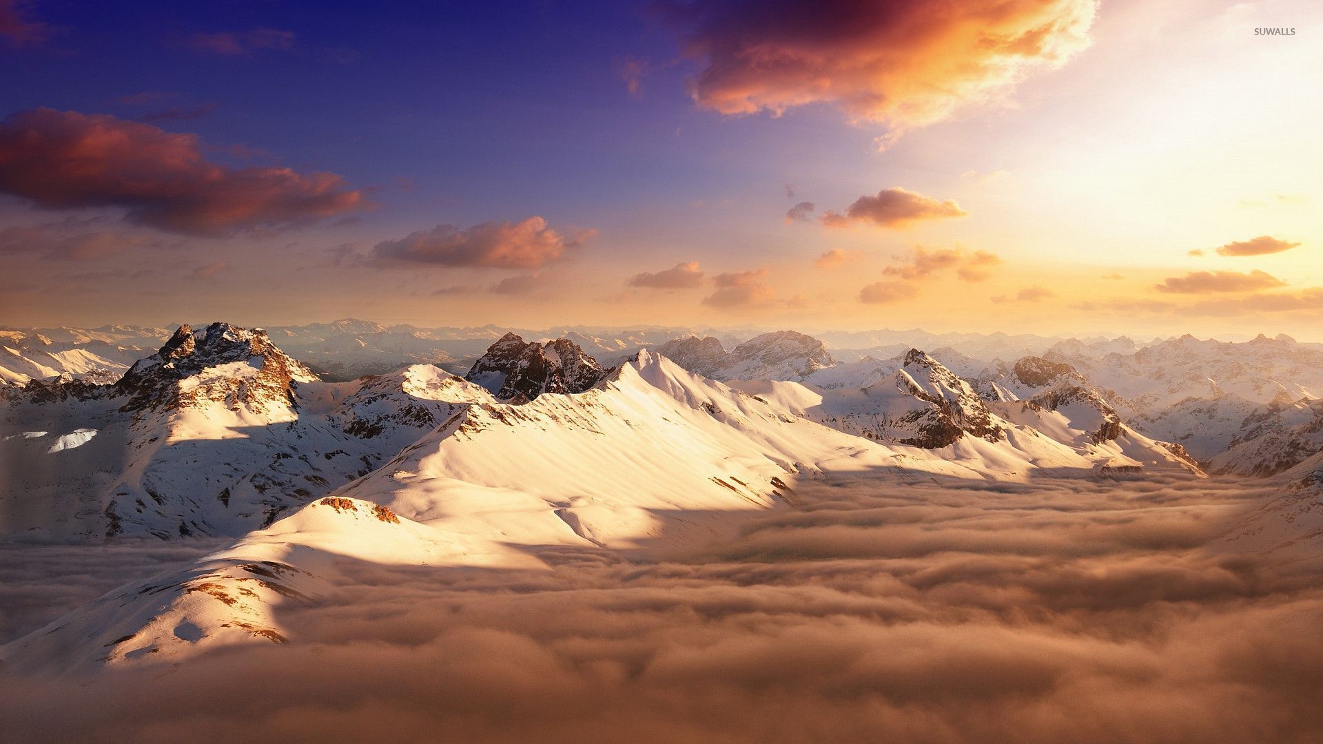 Snowy mountain peaks above the clouds wallpaper