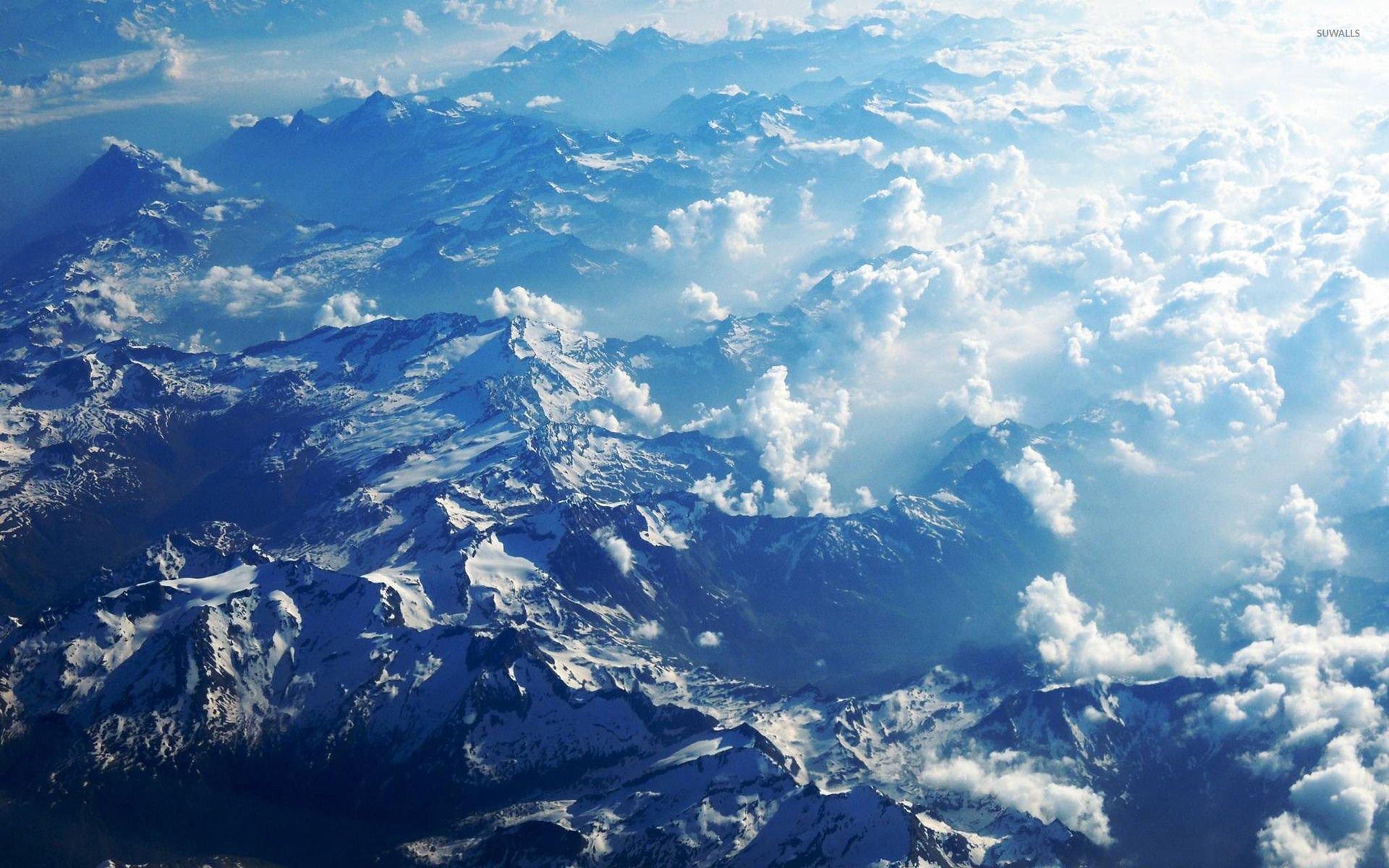 Fluffy clouds above the snowy mountains wallpaper