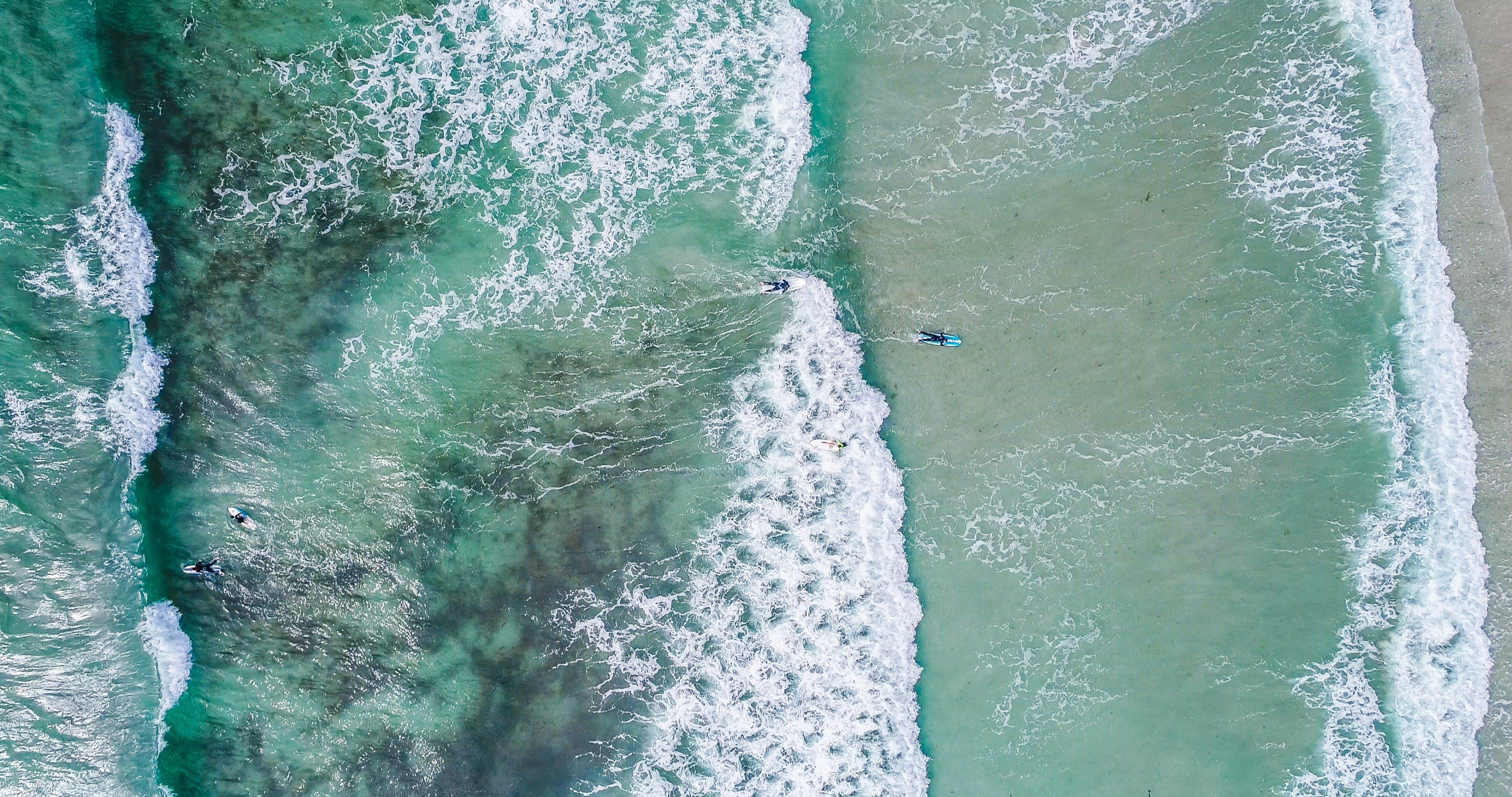 drone aerial view of surfers in the ocean at guernsey surf
