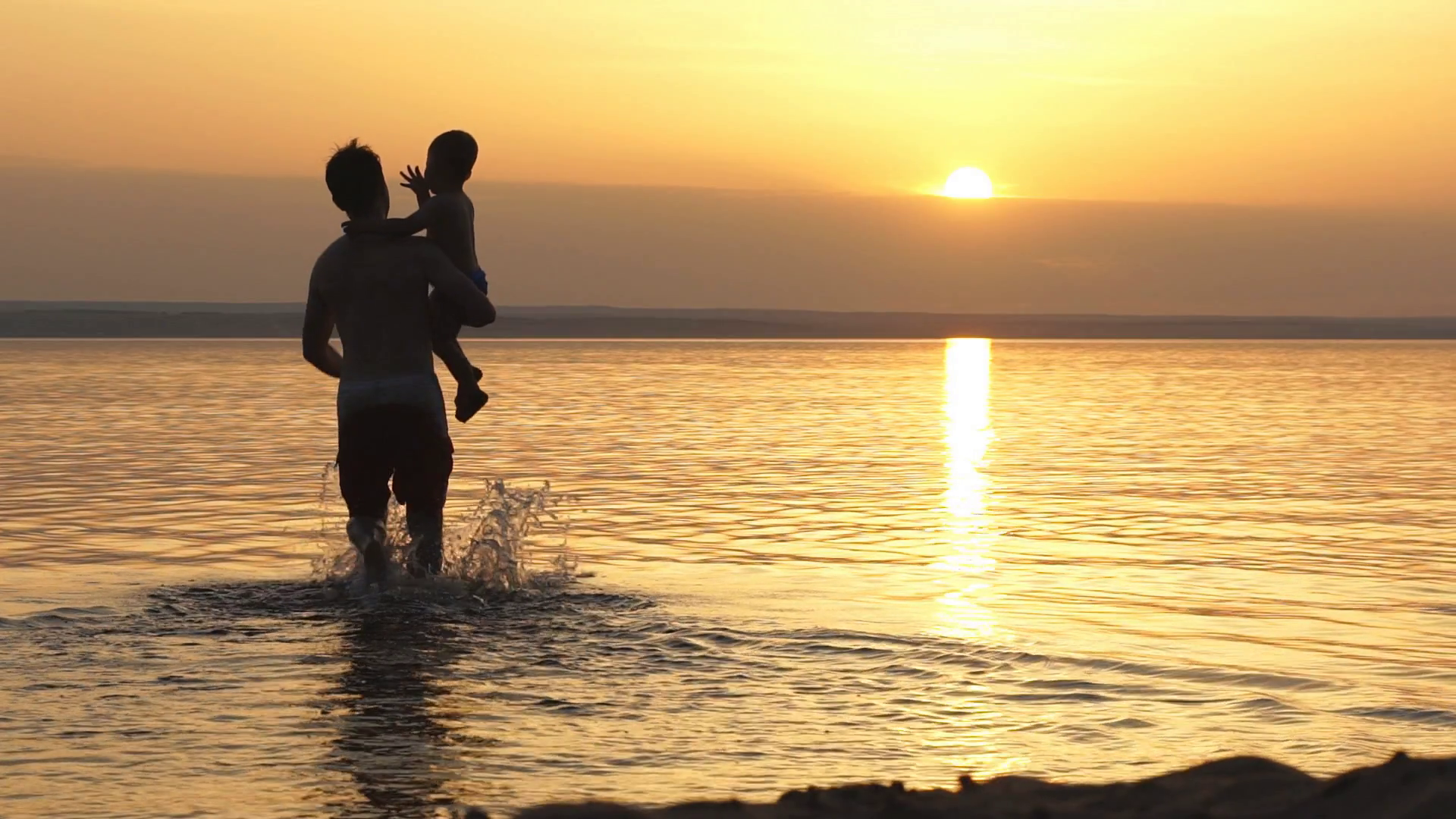 silhouettes of father and son on sunset sea background Stock Video