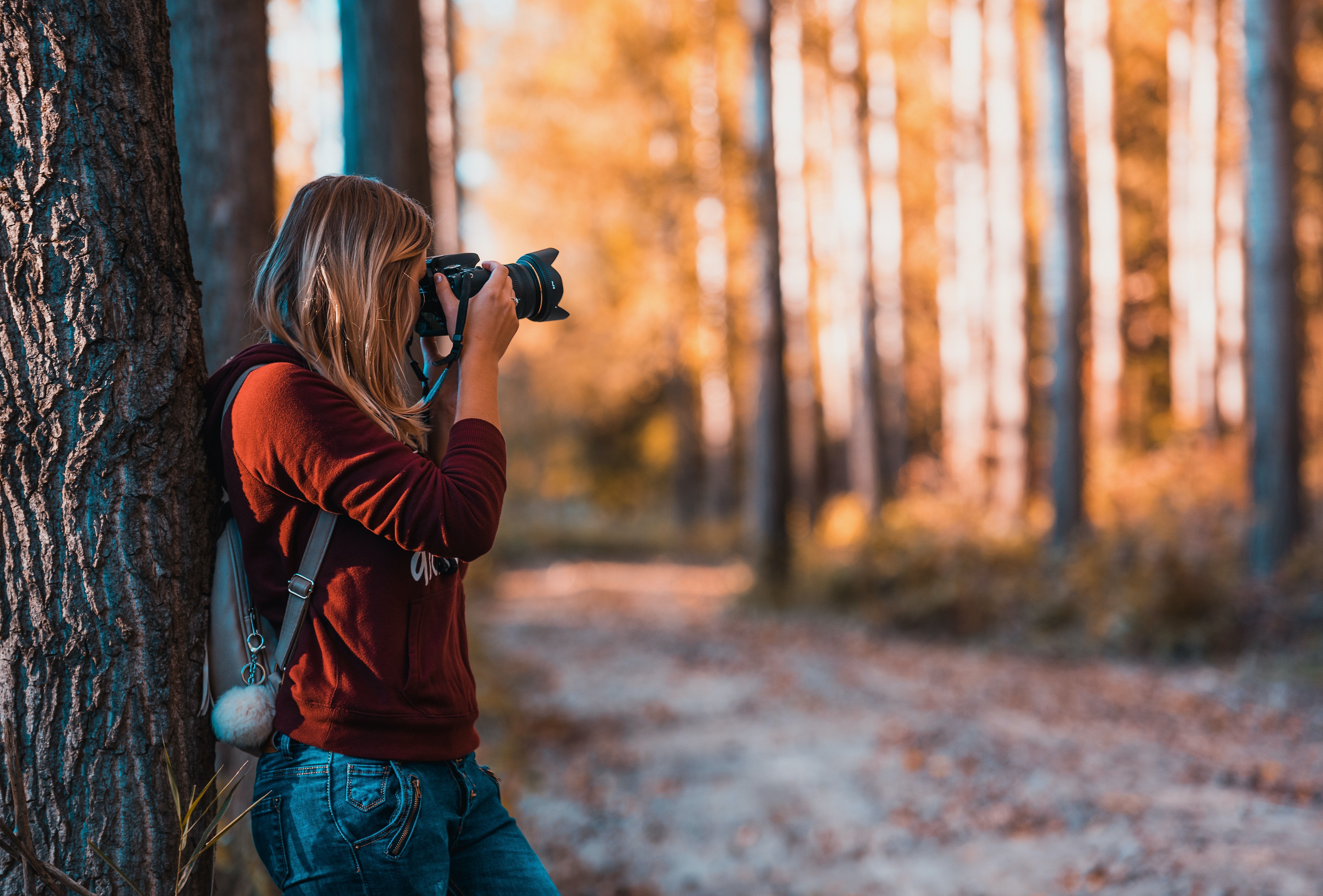 Woman Leaning Back on Tree Trunk Using Black Dslr Camera during