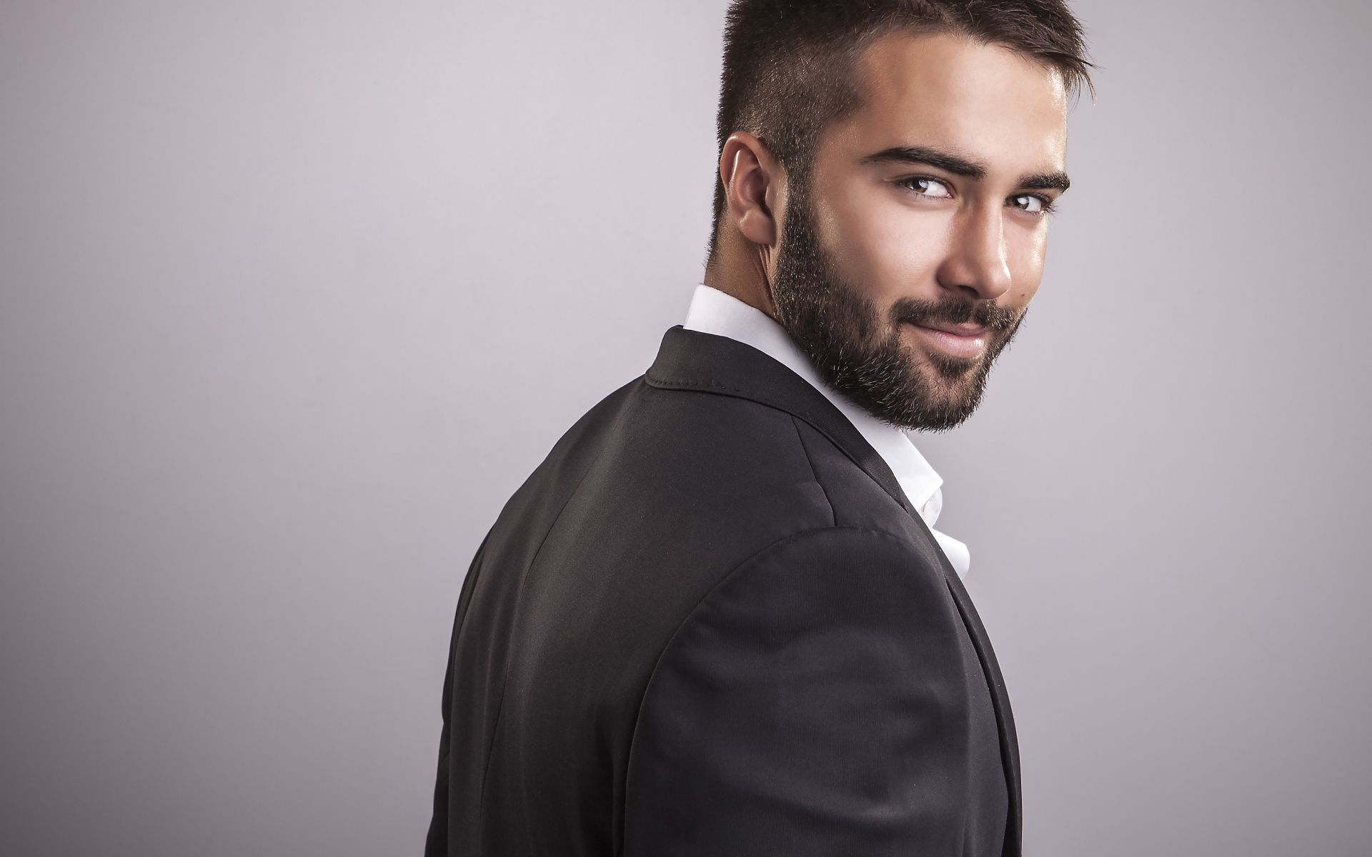 Handsome male model with a beard on gray background Desktop