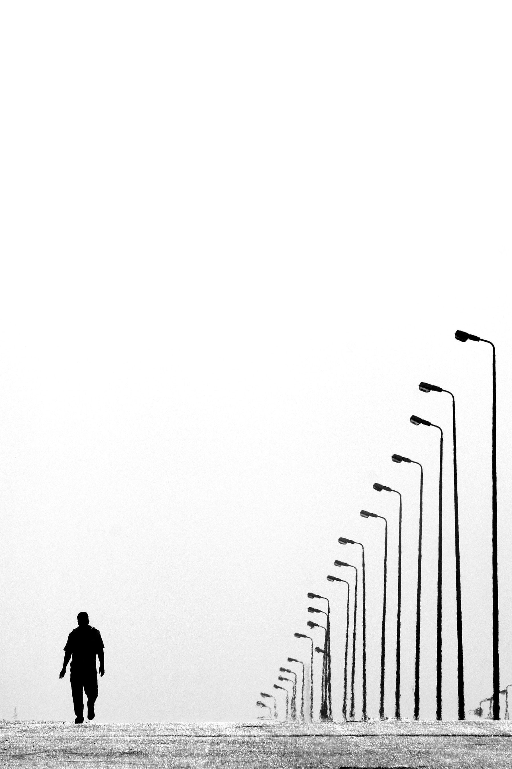 Man Walking Near Aligned Lamp Post · Free