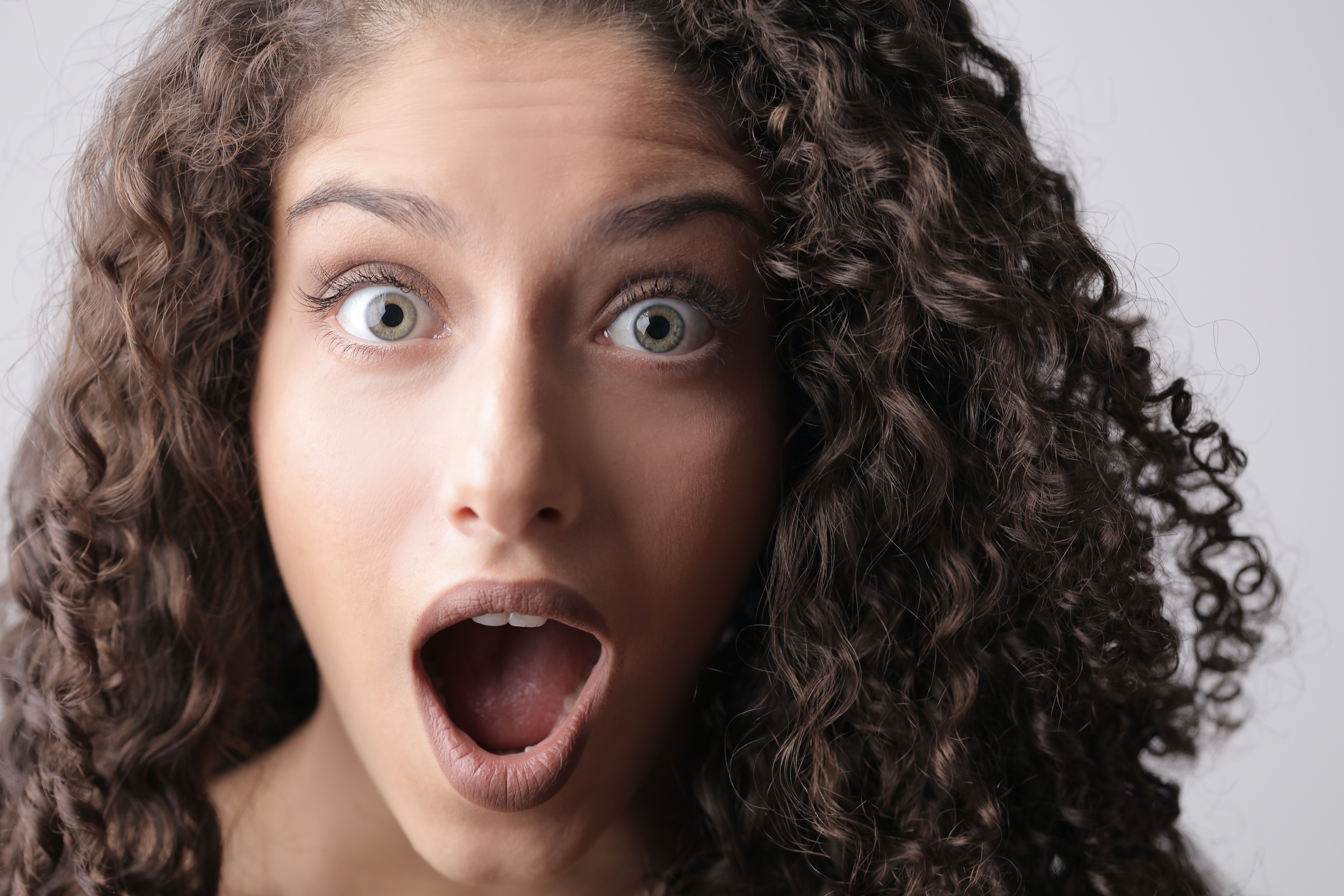 Close Up Photo Of Shocked Woman With Brown Curly Hair · Free Stock