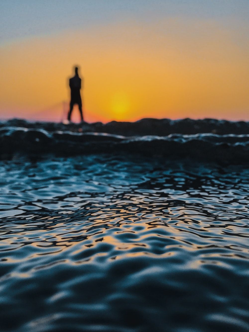 silhouette of man standing in docks during sunset photo