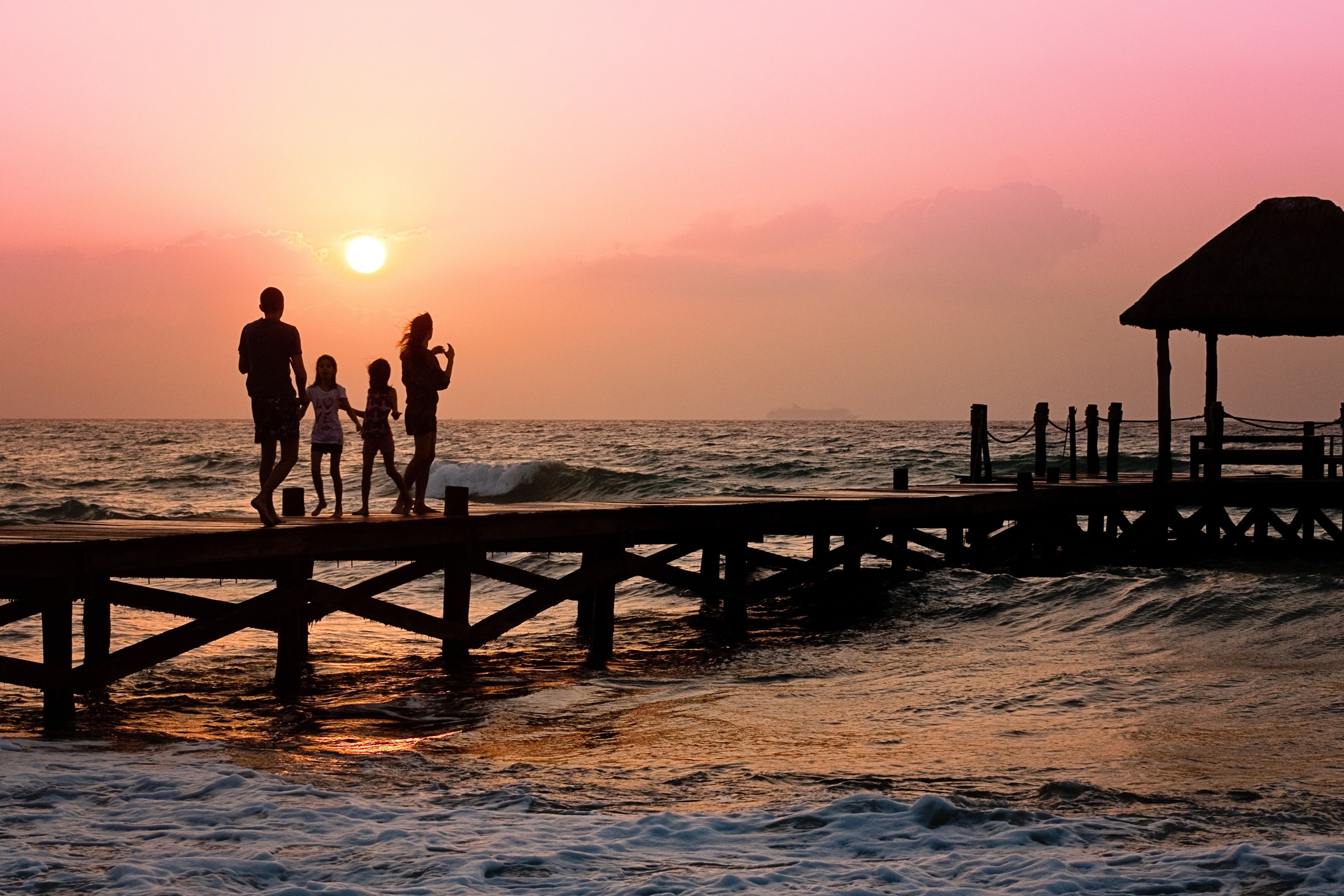 silhouette of 4 person walking on dock near sea during sunset free