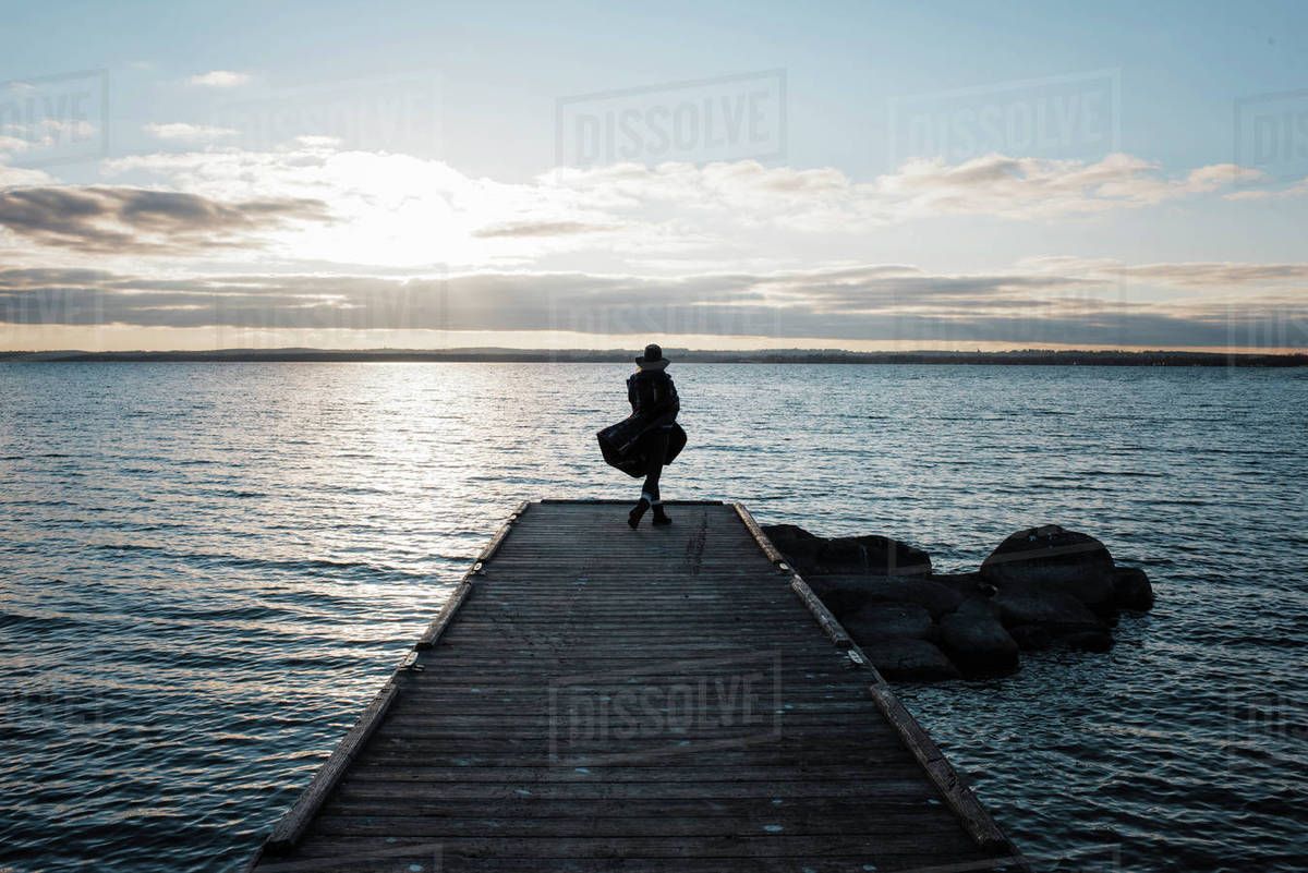 Rear view of woman wrapped in blanket standing on pier