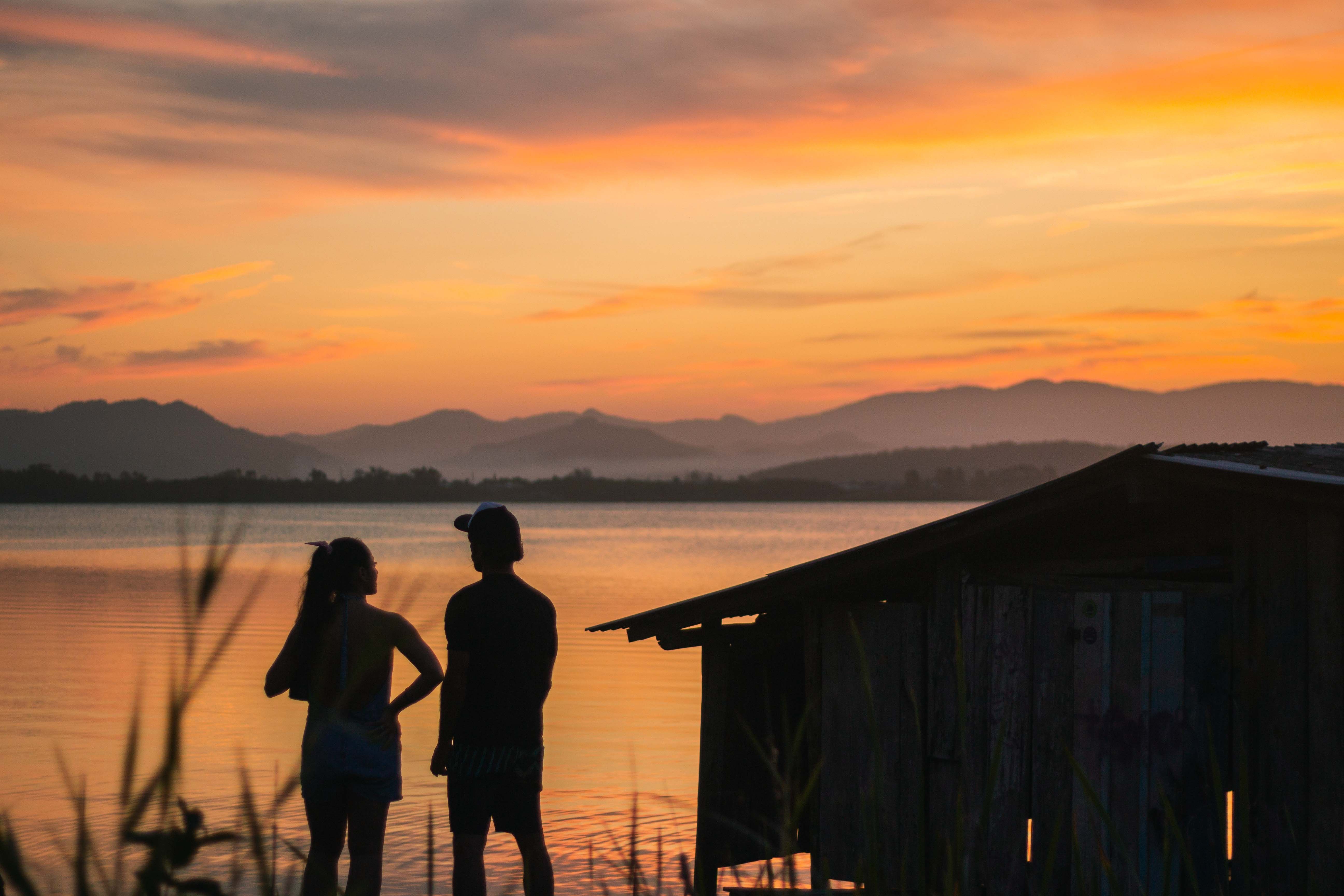 Silhouette of 2 Person Standing on Wooden Dock during Sunset