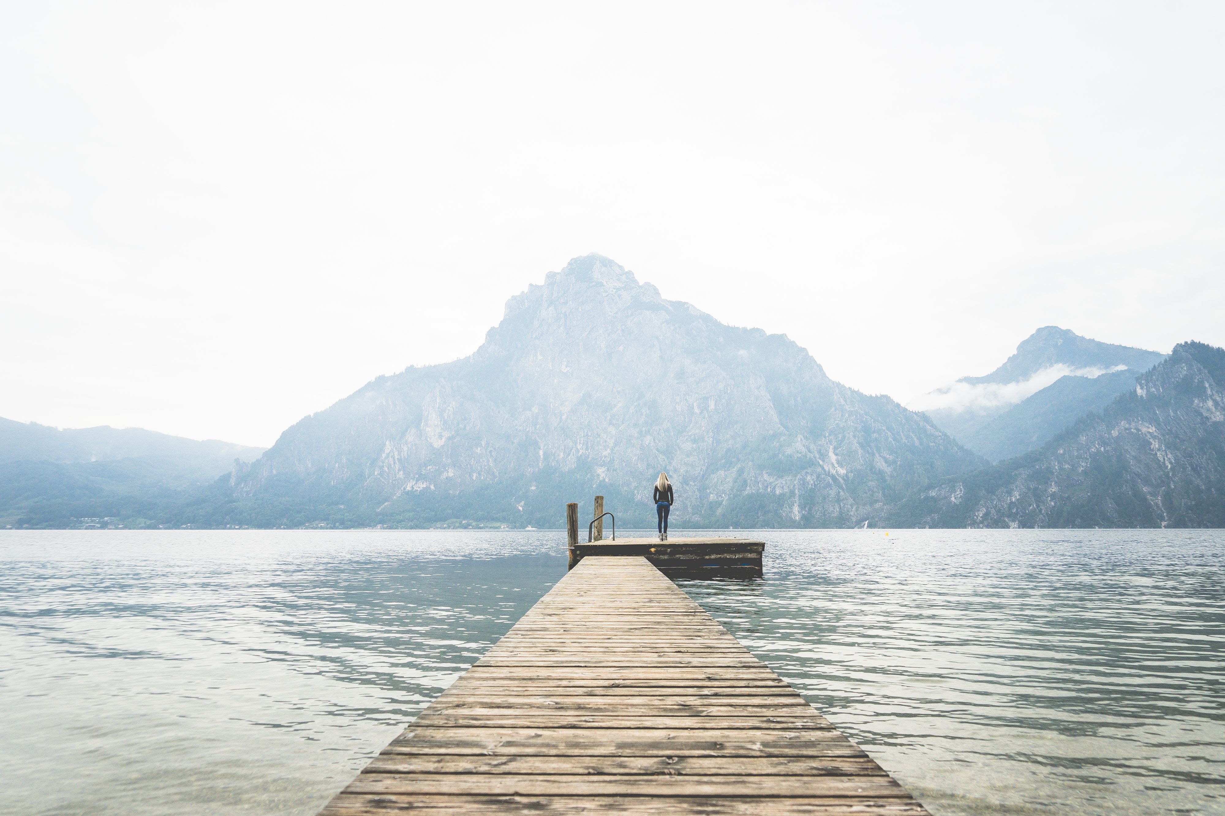 Woman Standing Alone on a Large Wooden Pier on a Lake Free Stock