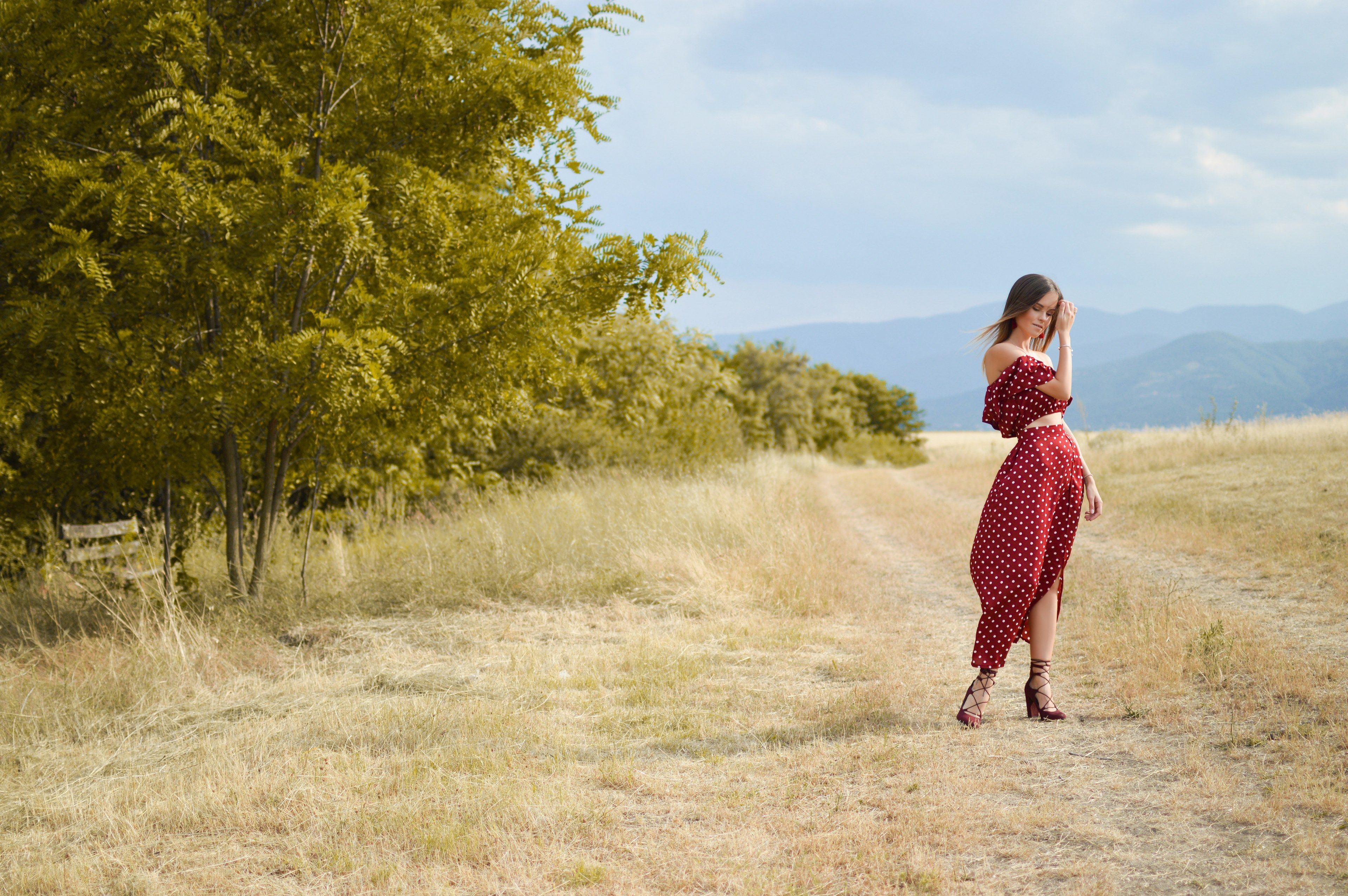 woman models a red flowy outfit in a windy fieldmiddle summer