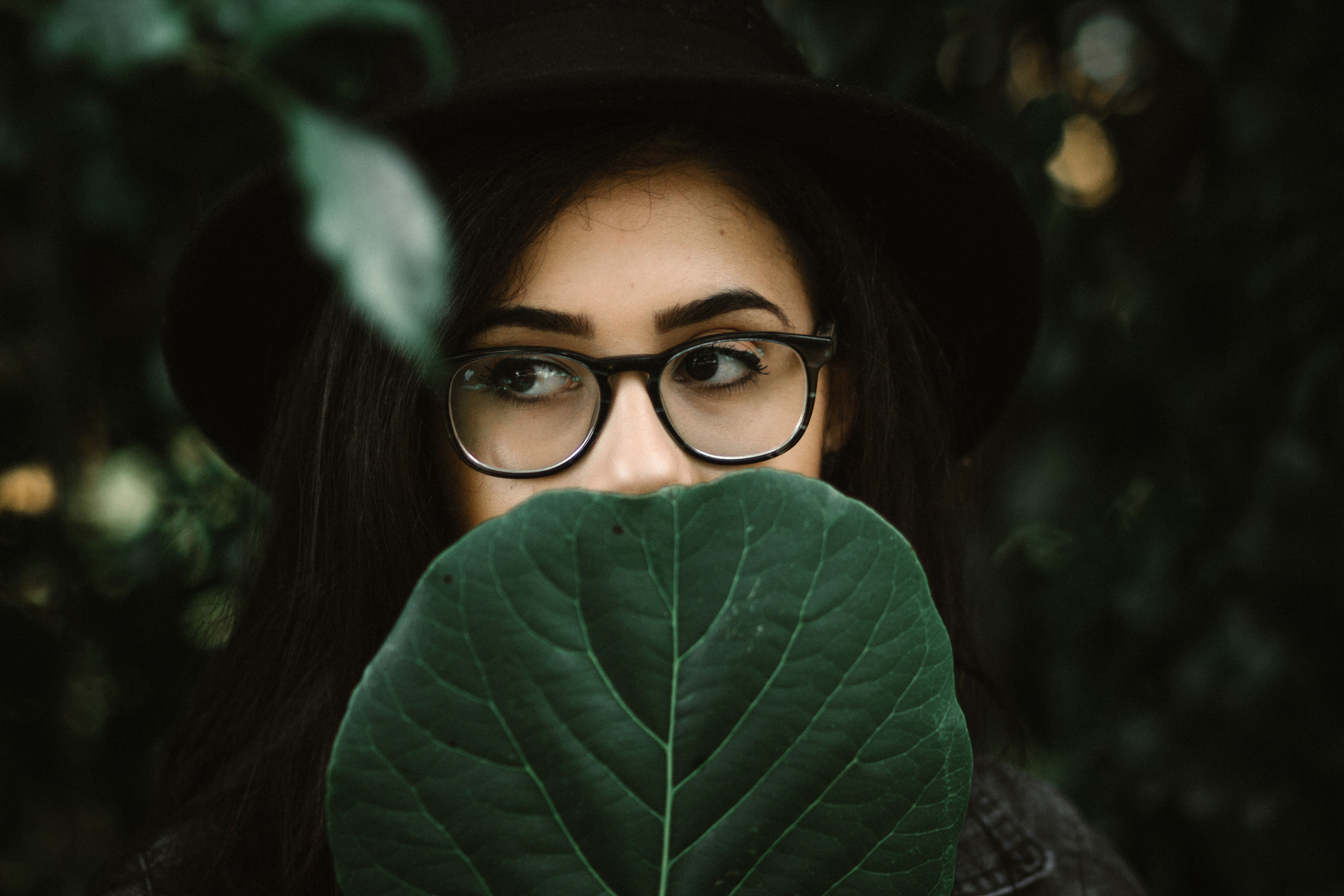 woman wearing black framed eyeglasses covering her face with green
