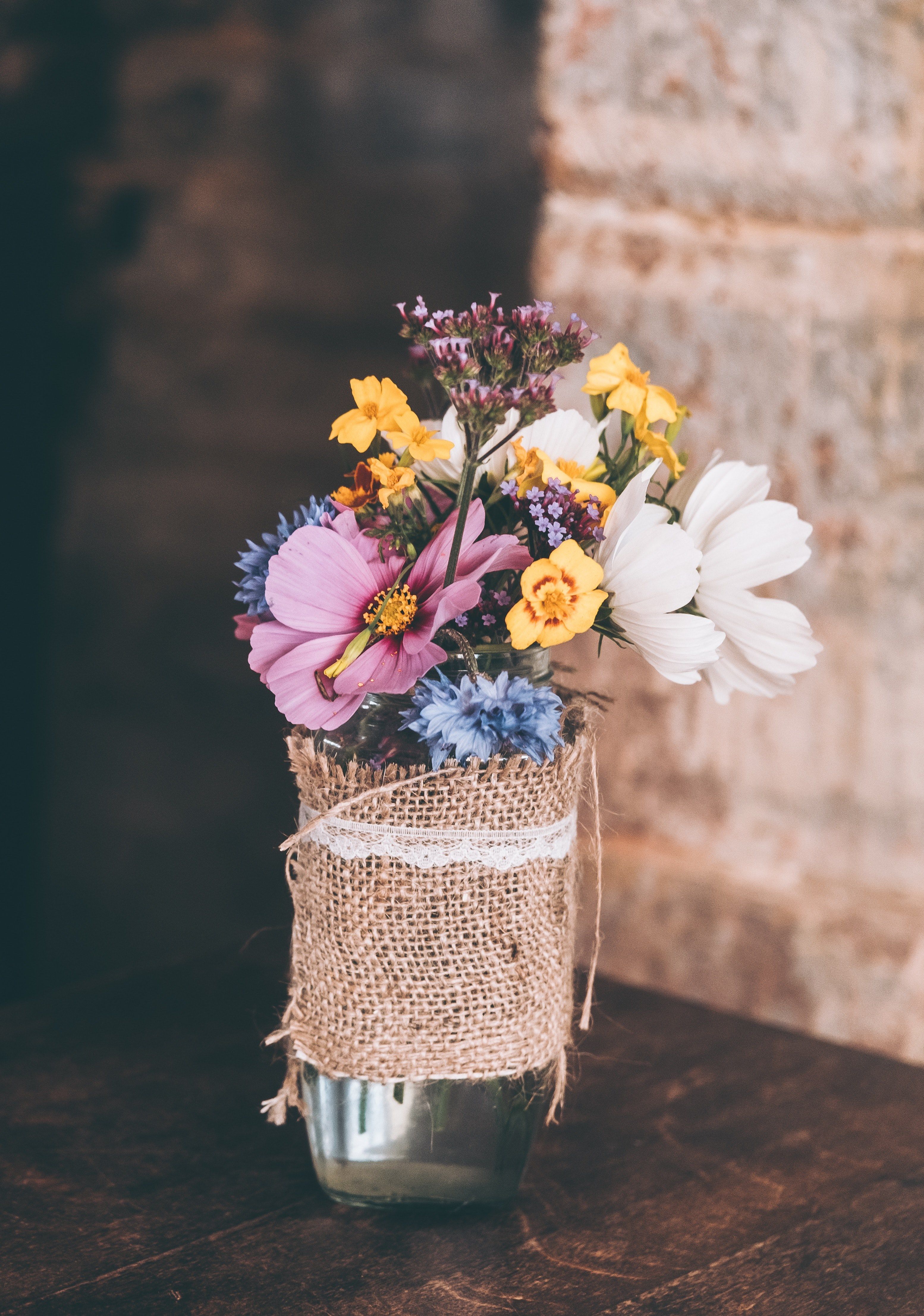 a bouquet of various flowers in a glass vase on a wooden