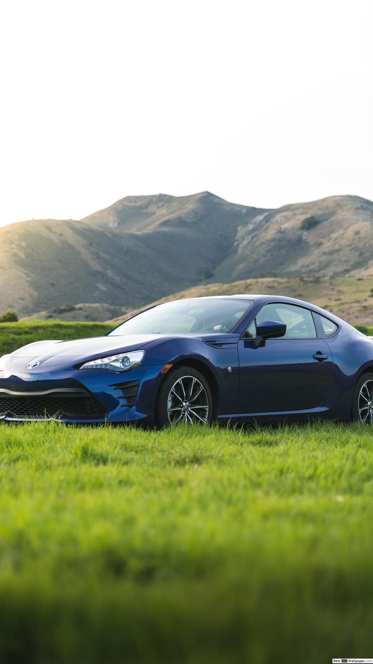 Blue Toyota 86 coupe on green grass near mountain at daytime HD