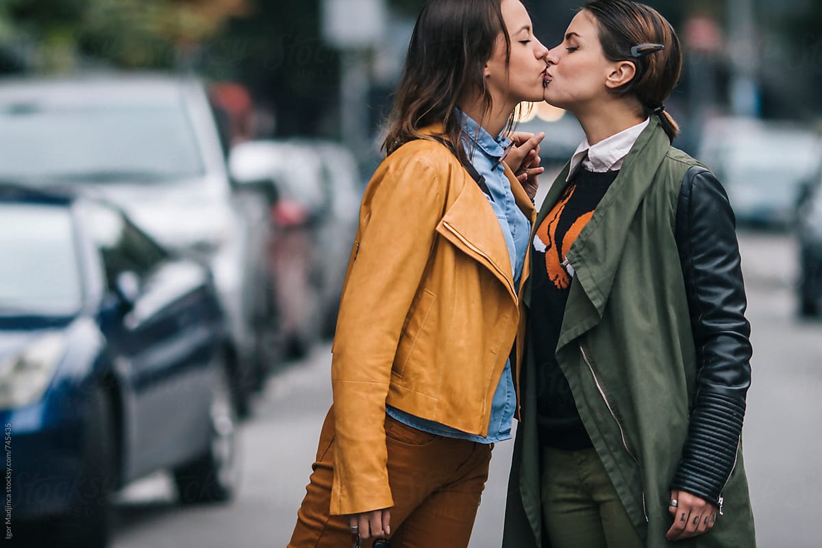two colorfully dressed girls in love kissing on the street