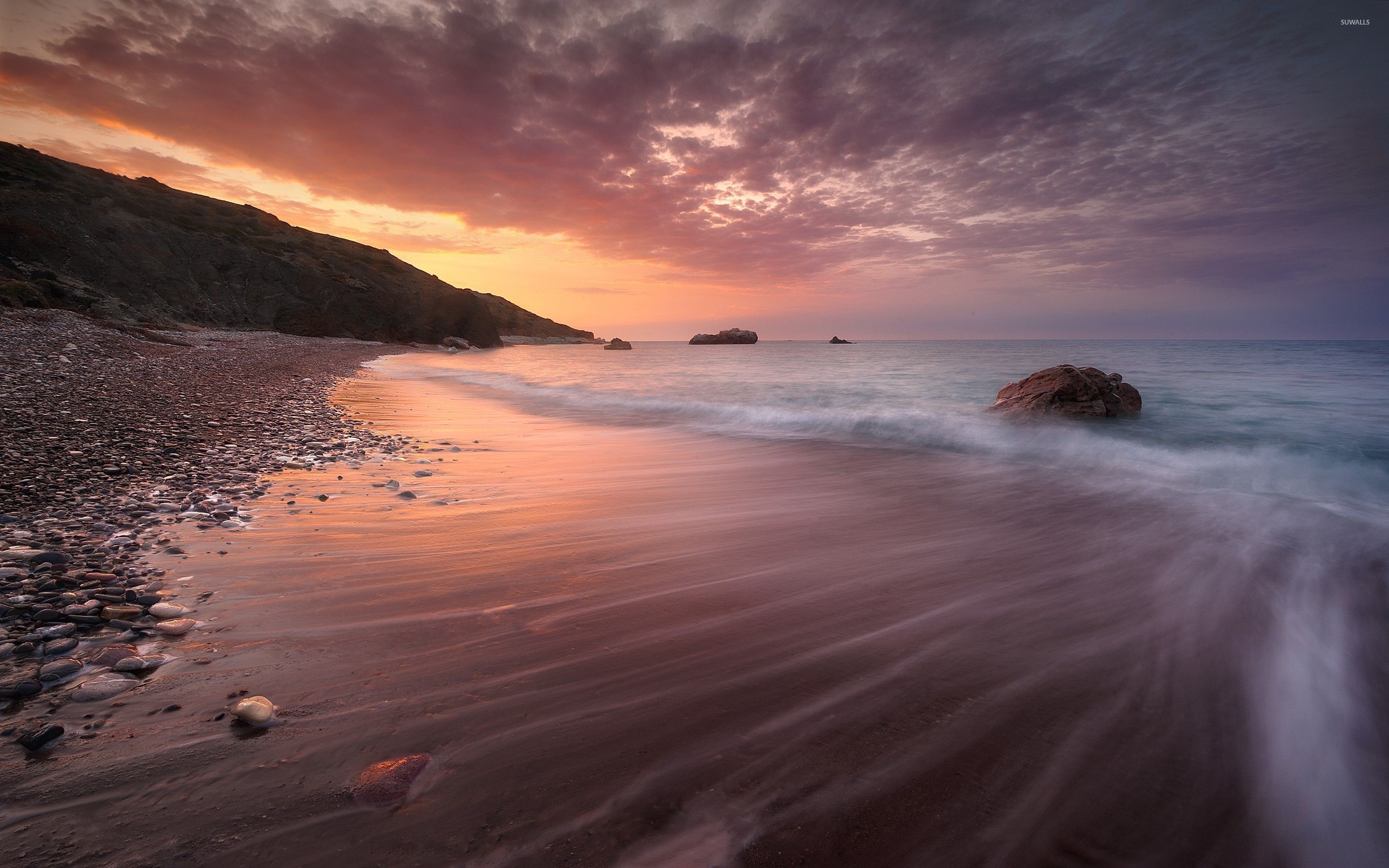 Sandy beach splitting the ocean from the rocks wallpaper