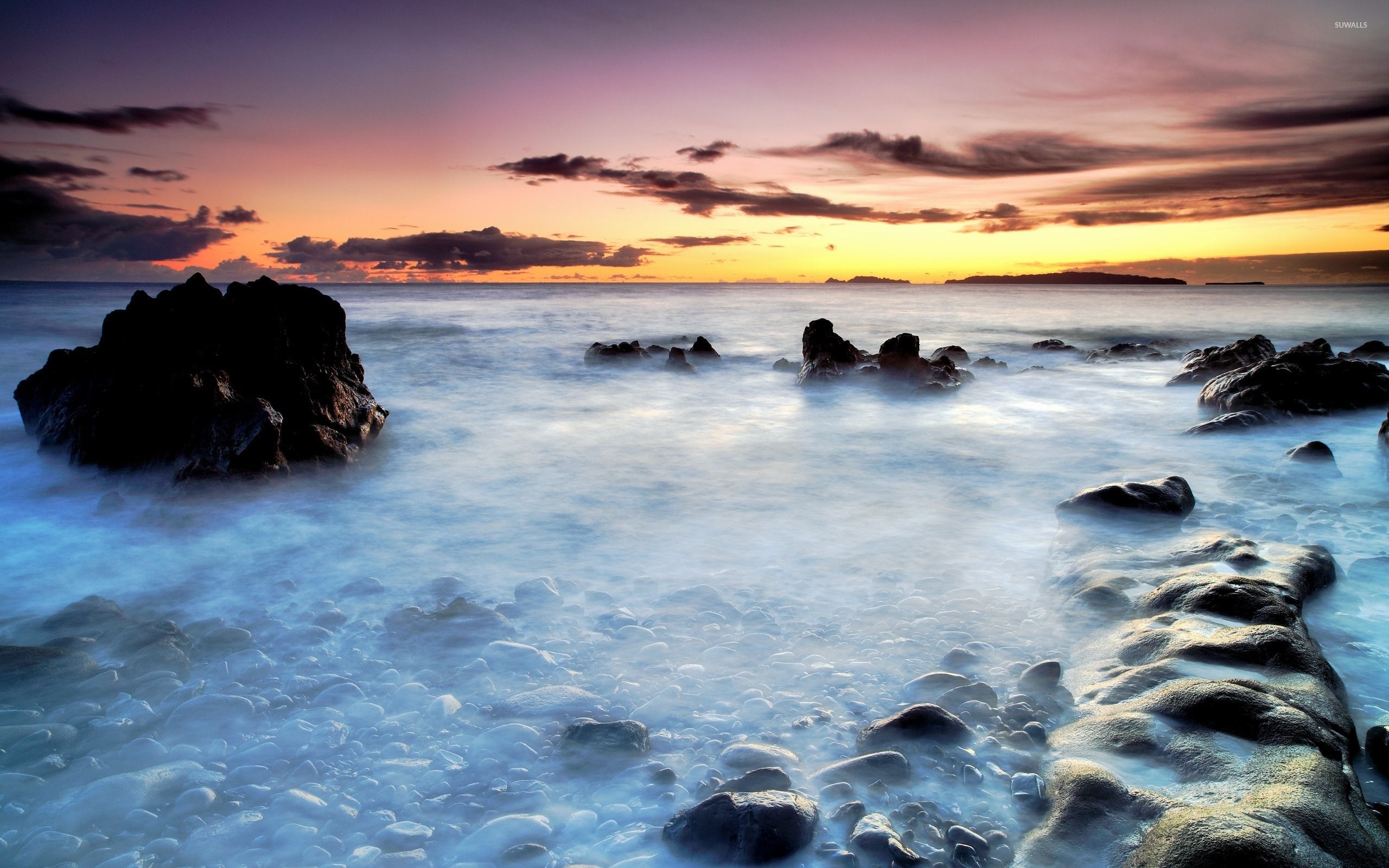 Rocks rising towards the sunset from the mysterious ocean