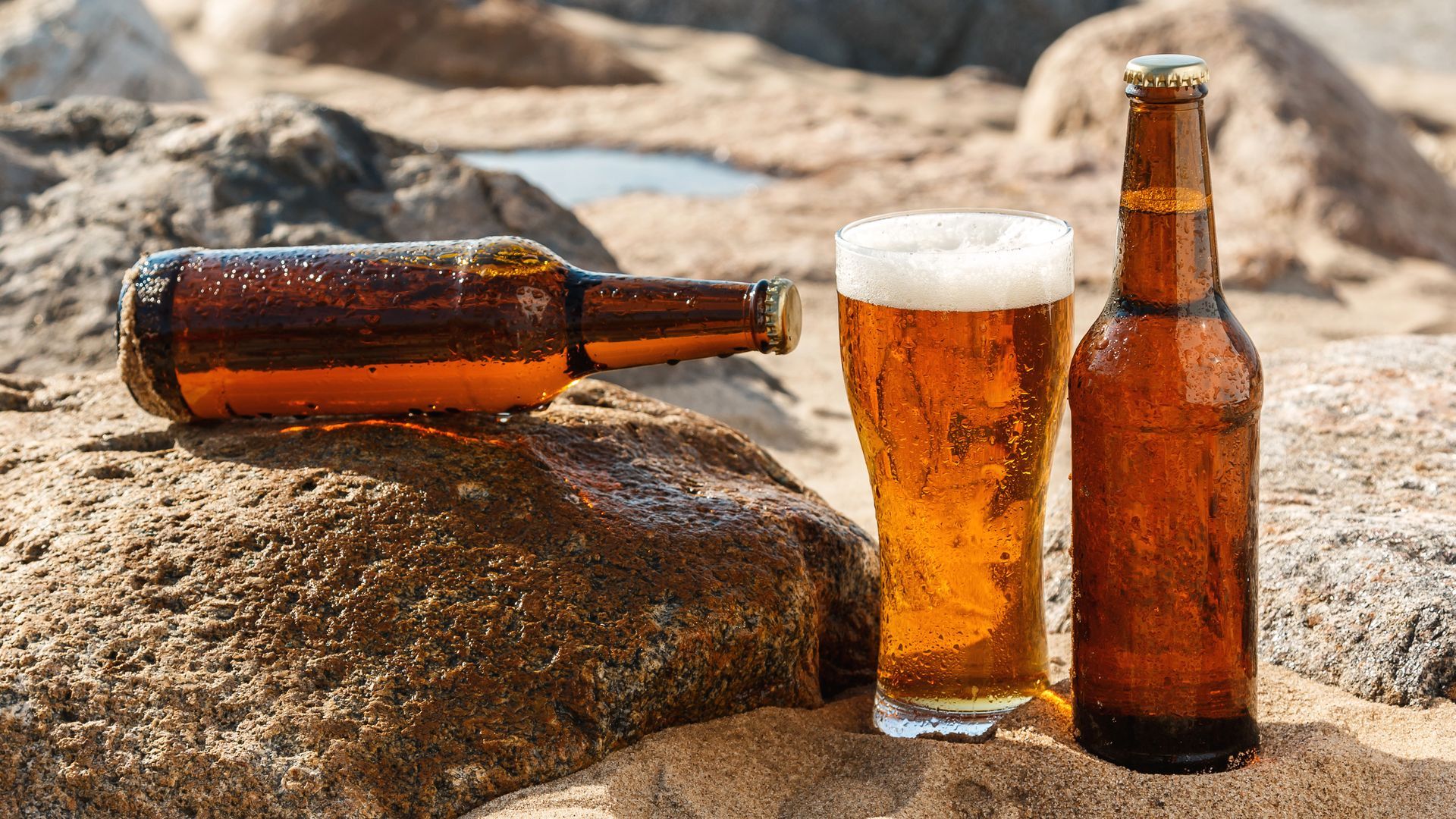 Beer Bottles and Glass on Rock Sand Wallpaper