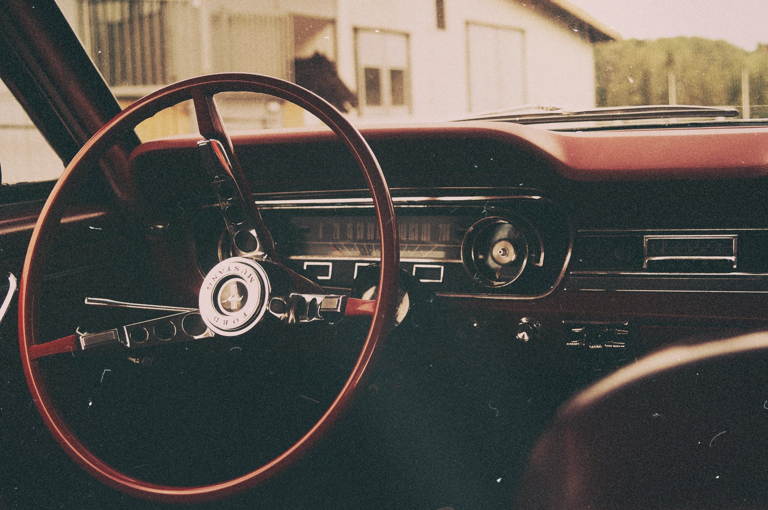Wallpaper / ford mustang vintage automobile car interior shot focusing on the thin wheel with a barn of horses in the backgrounddshield, back in the feauture 4k wallpaper
