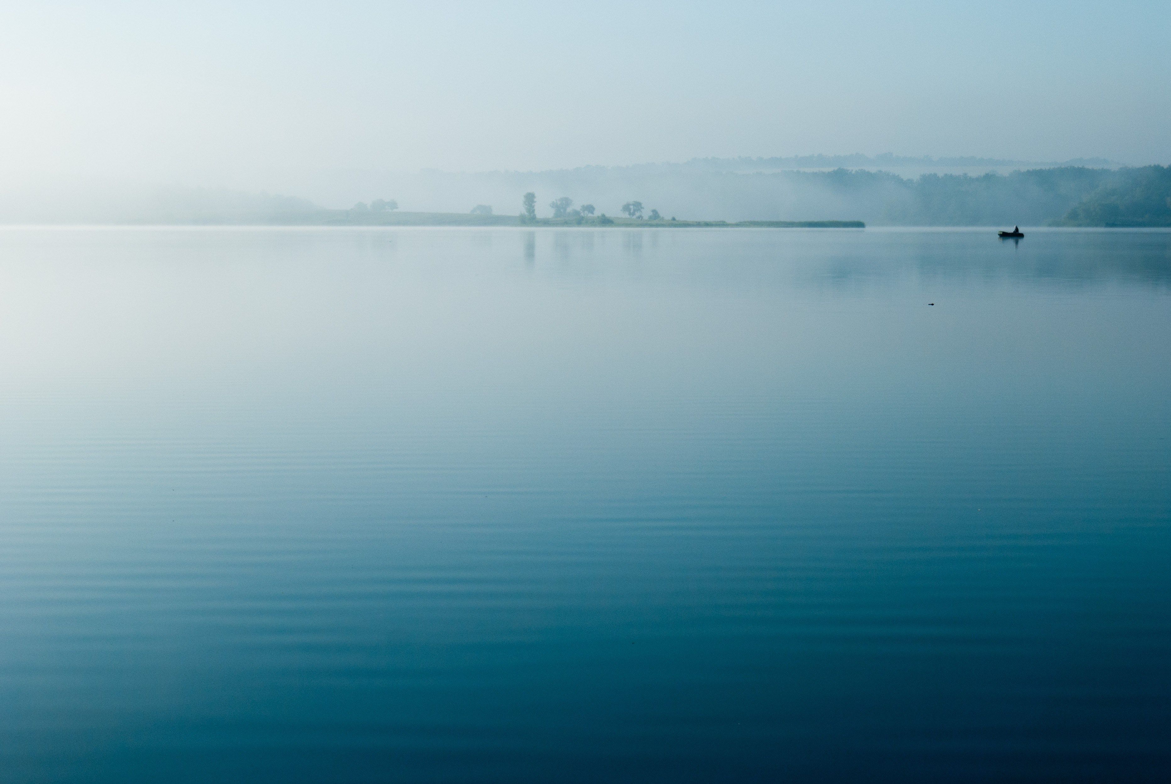 Wallpaper / boats sit in calm blue waters on a misty evening, early morning lake 4k wallpaper