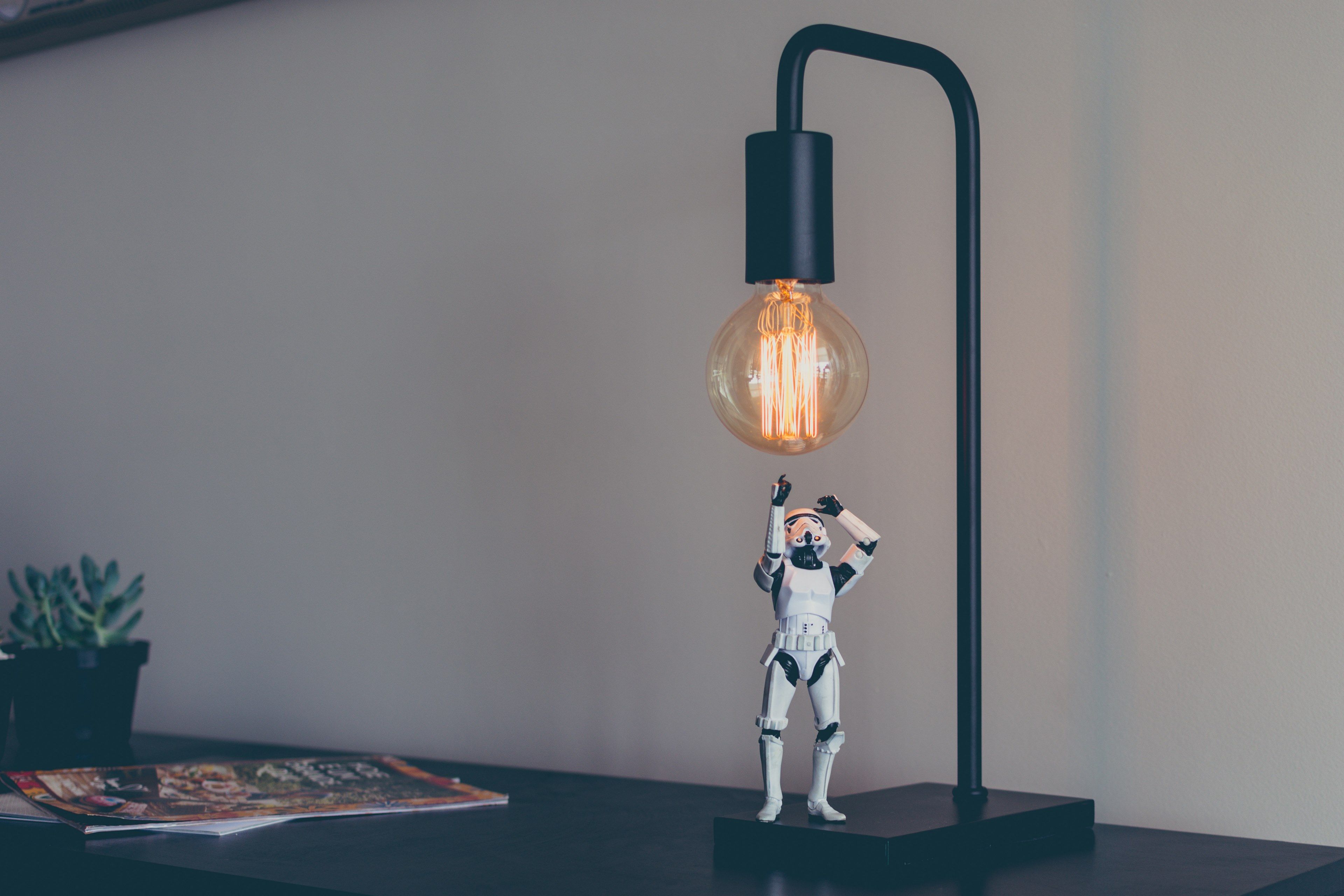 Wallpaper / a figurine of a stormtrooper under a desk lamp with an incandescent light bulb, bright idea 4k wallpaper