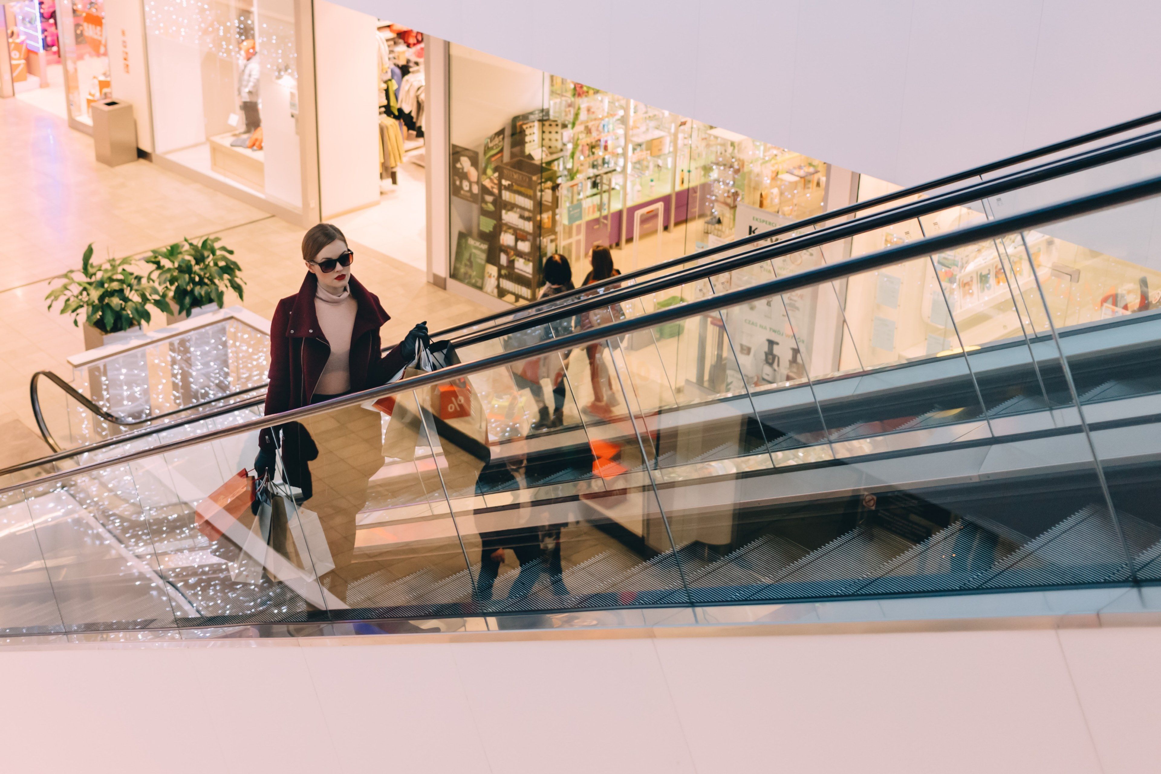 Wallpaper / chic woman in sunglasses holds bags up a mall escalator, mall shopping 4k wallpaper