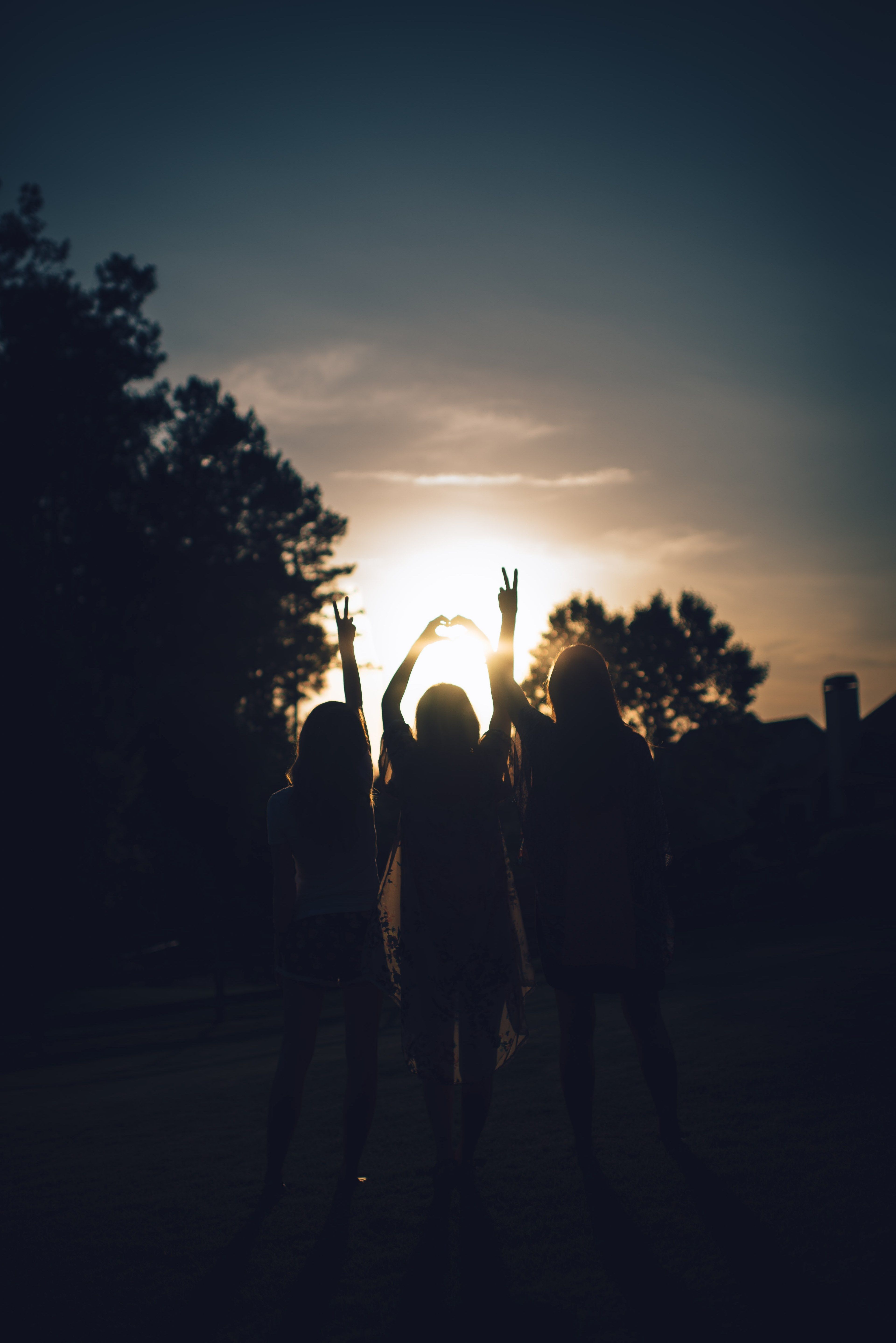 Wallpaper / silhouette of three girls holding up peace signs and a heart hand sign during sunset, love and peace in the sunset 4k wallpaper