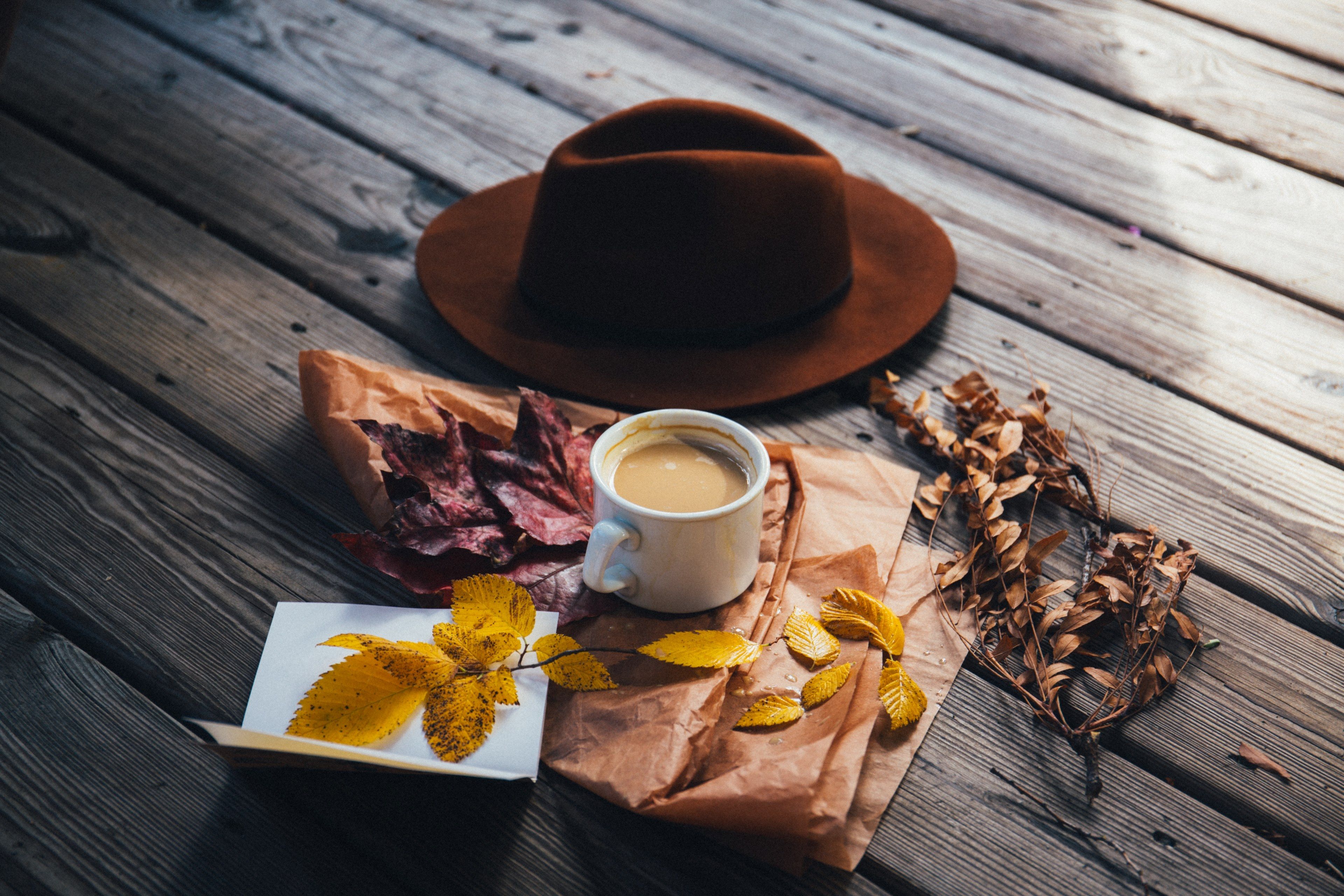 Wallpaper / a brown cowboy hat a cup of coffee and autumn leaves laid out on a wooden surface, hat leaves and coffee in flatlay 4k wallpaper