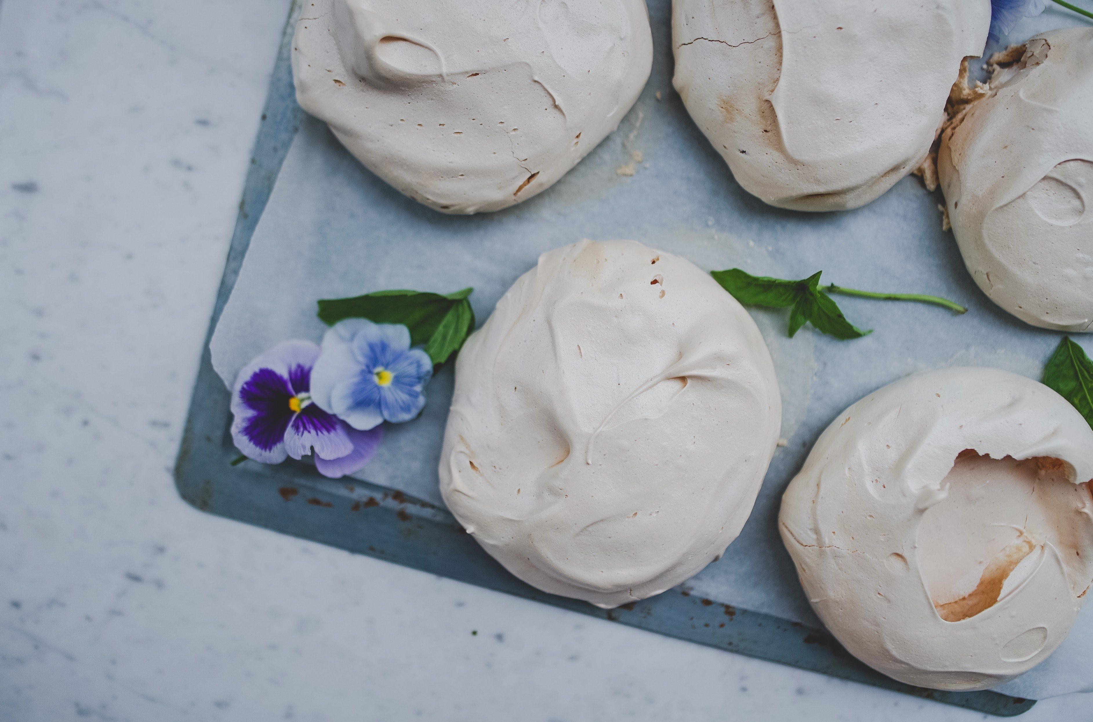 Wallpaper / an overhead shot of several meringues and violet flowers on a baking tray, naked pavlova 4k wallpaper