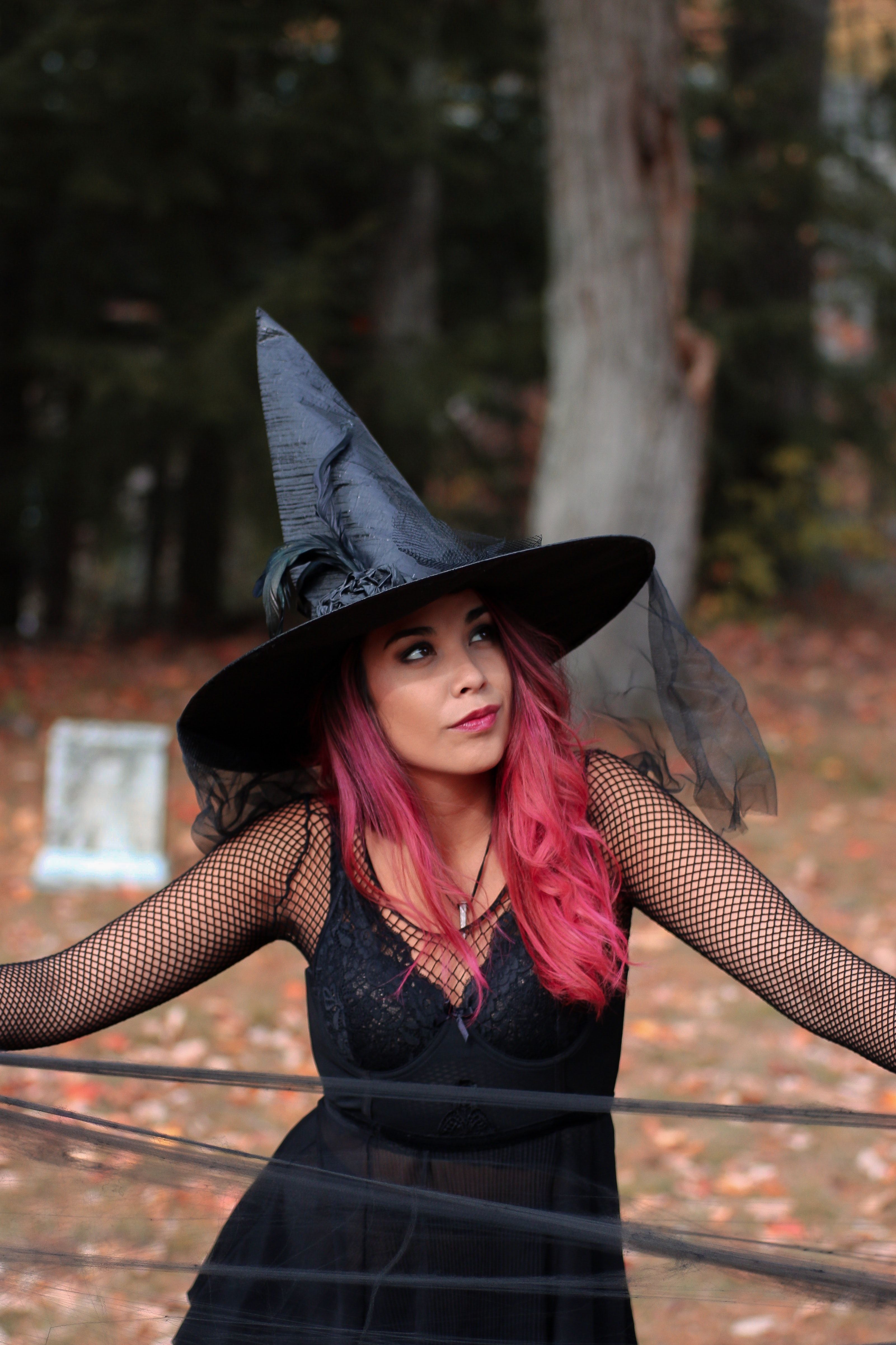 woman in black spaghetti strap dress and wearing witch hat photo