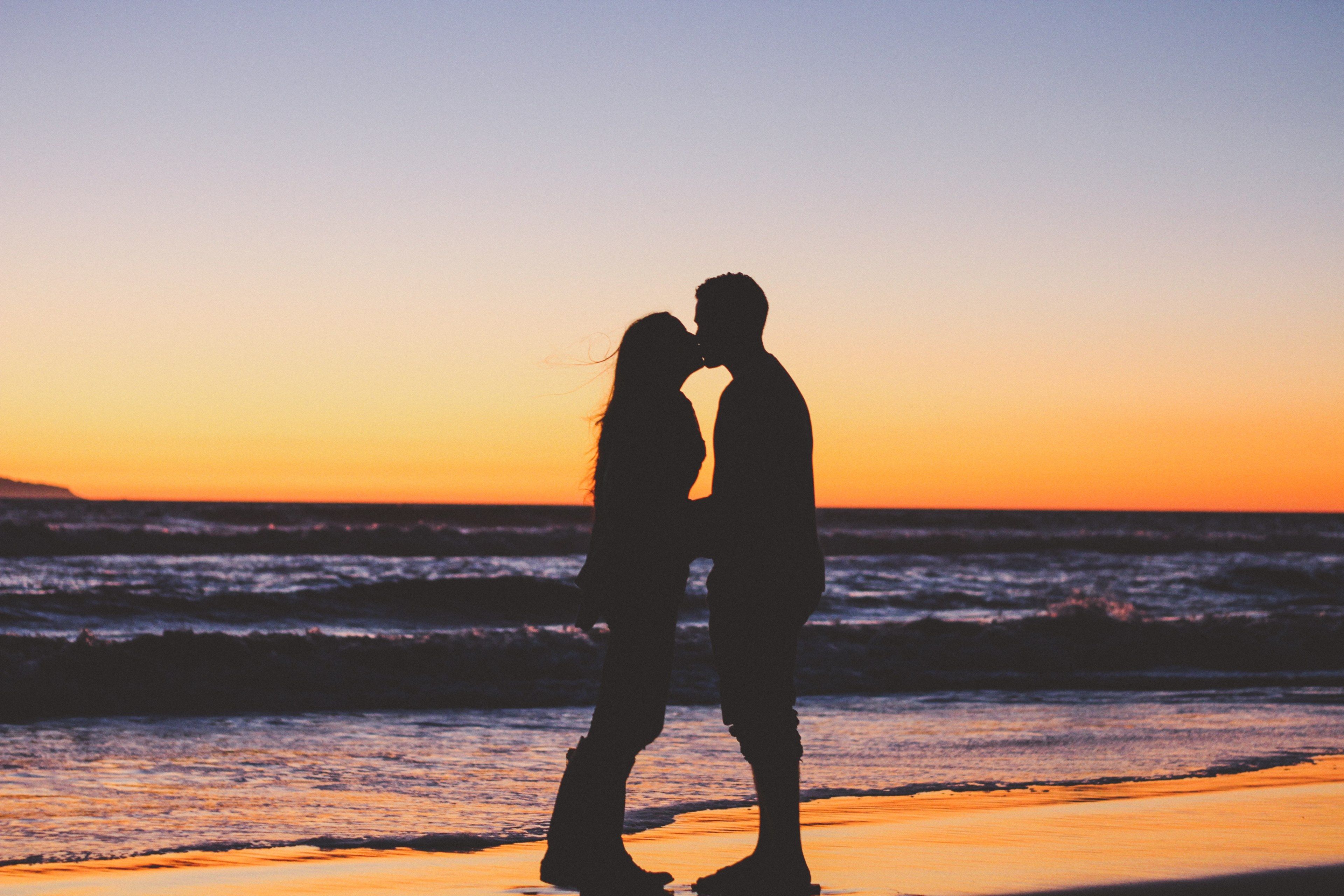 Wallpaper / girlfriend and boyfriend share a kiss at sunset on the beach in silhouette, happily ever after 4k wallpaper