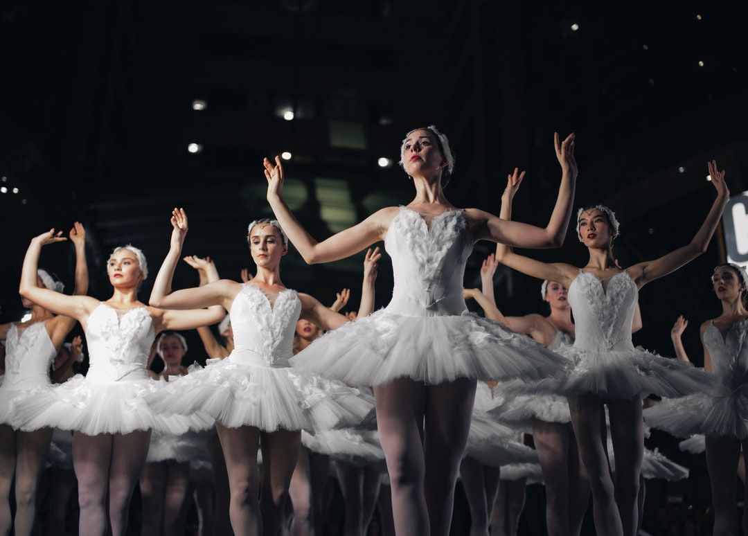 group of ballerinas dancing while raising both hands photo
