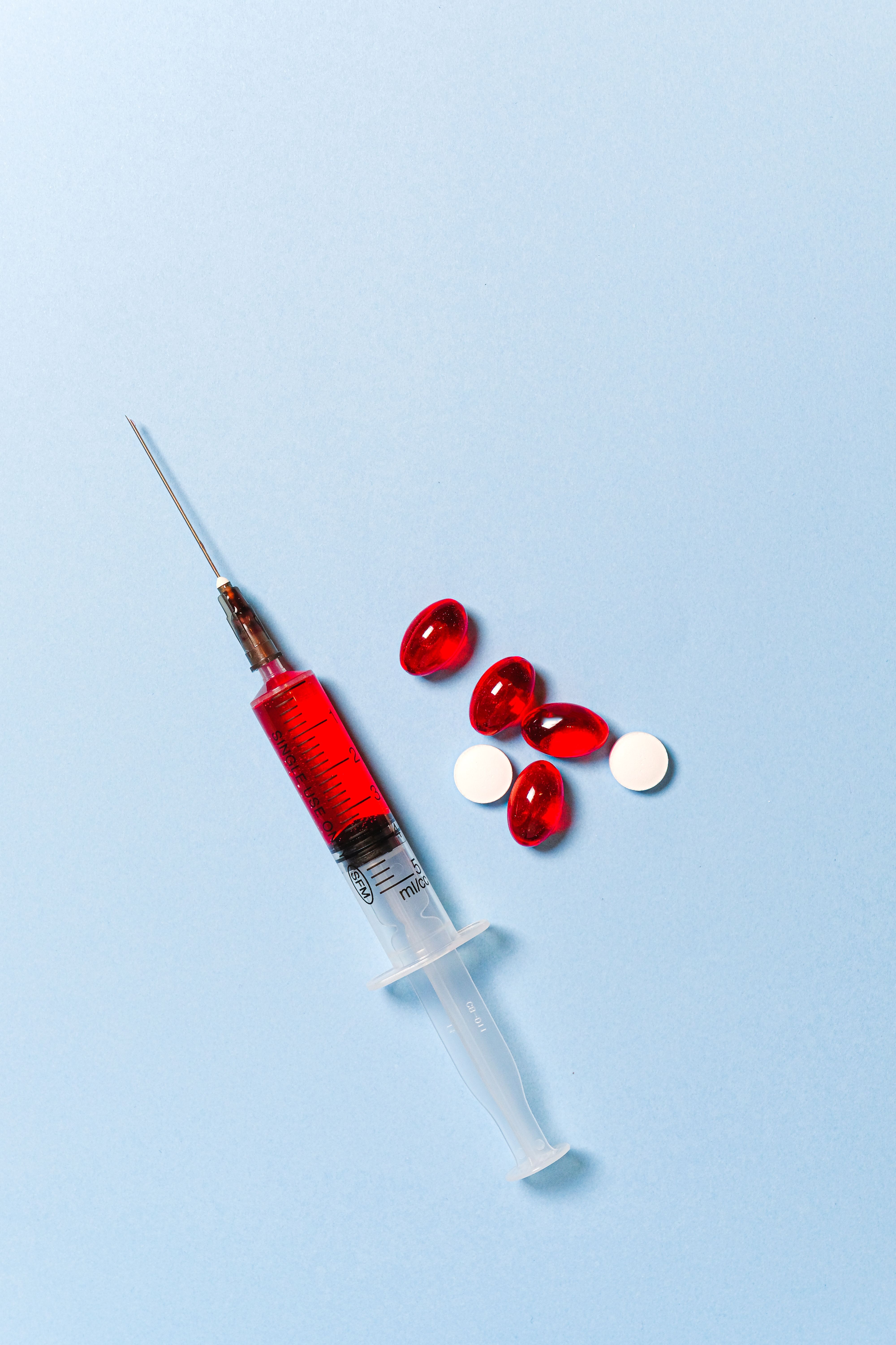 Syringe and Pills on Blue Background · Free