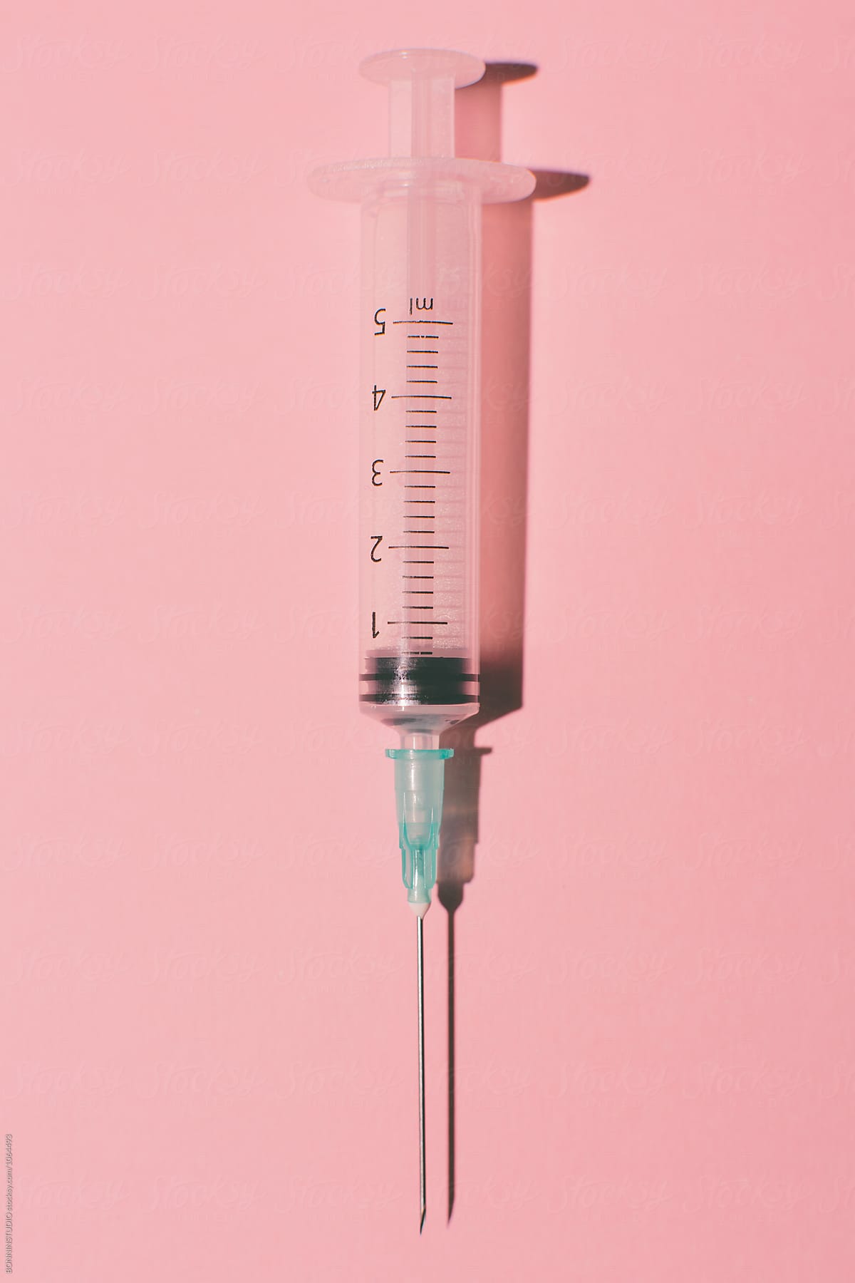 Syringe on pink background from above. by BONNINSTUDIO, Syringe
