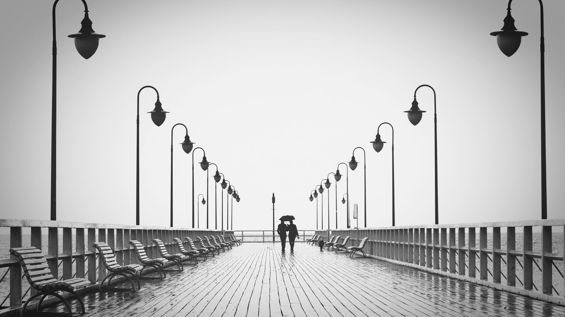 Two People Walking on Pier in Rain Wallpaper