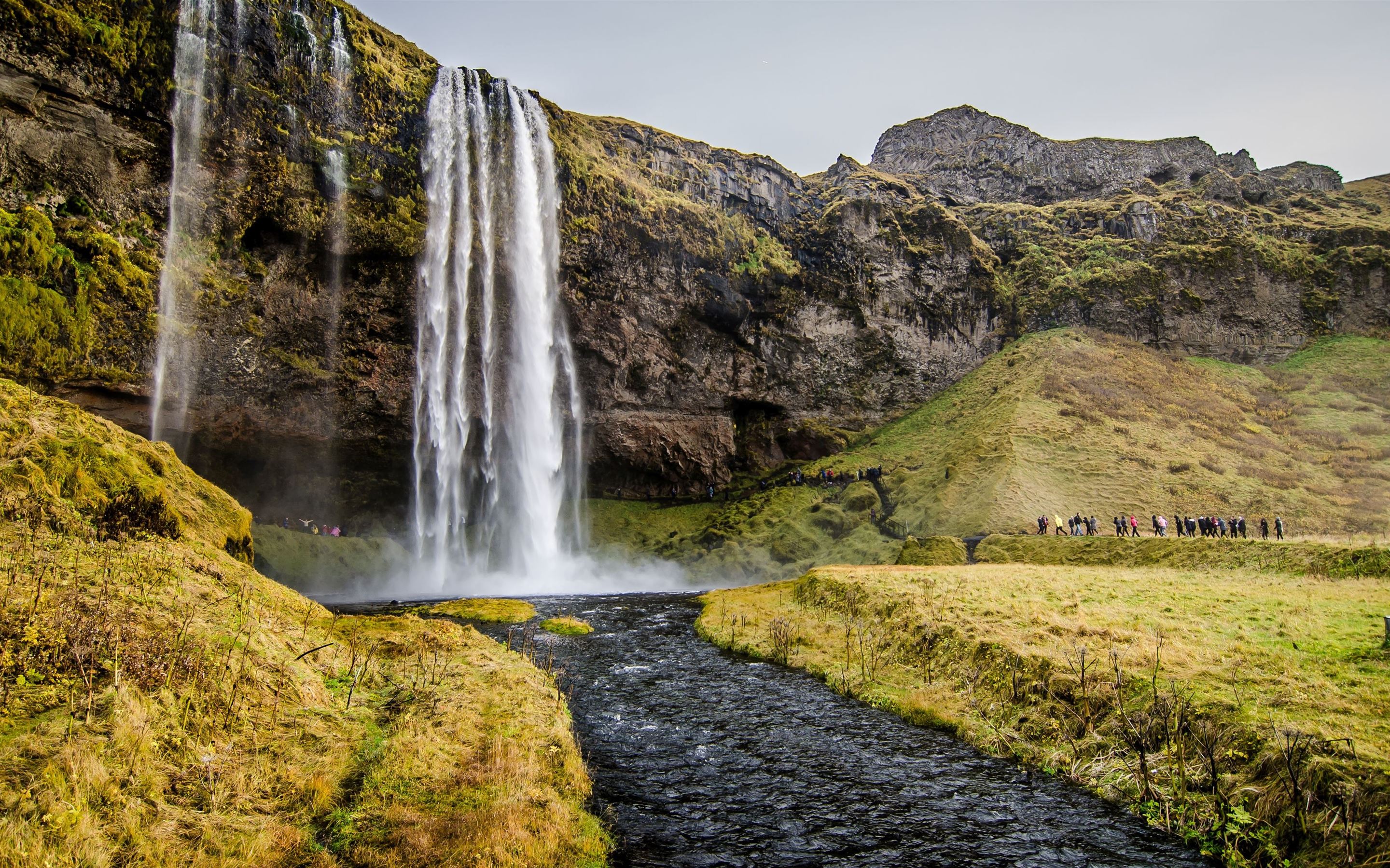 people walking towards waterfalls during daytime MacBook Pro Wallpaper Download