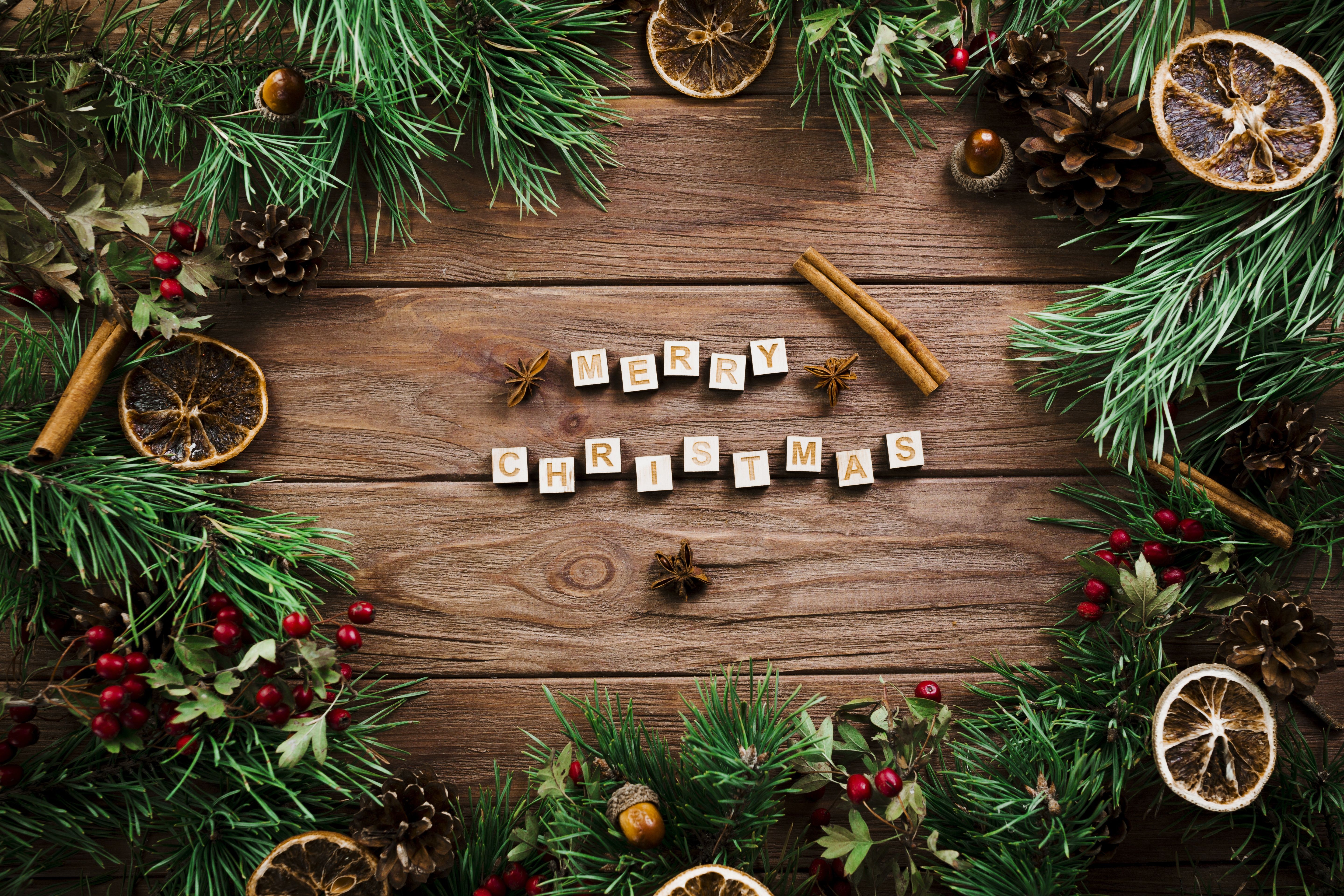 Merry Christmas lettering on a wooden table with fir branches. Desktop wallpaper 1400x1050