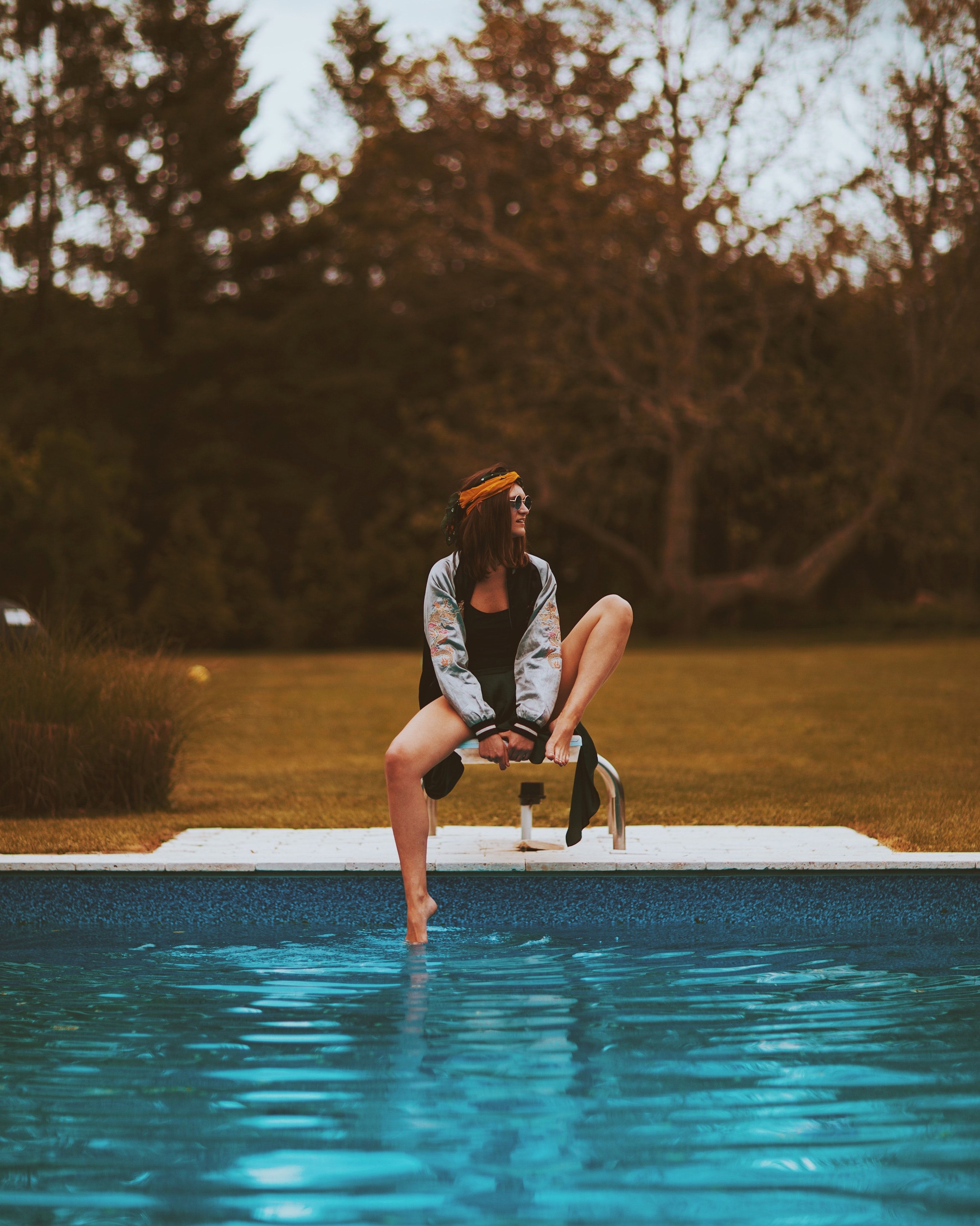 woman sitting beside swimming pool photo
