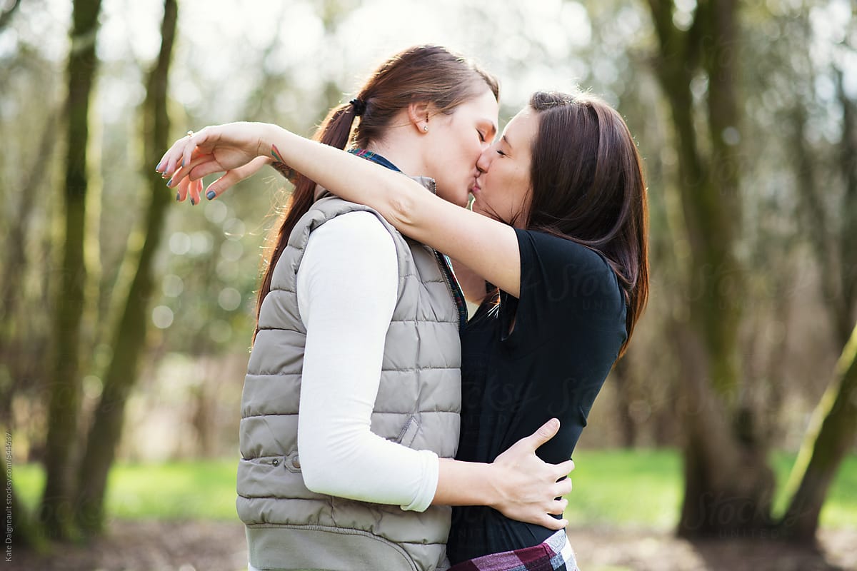 Attractive young lesbian couple kiss in the park