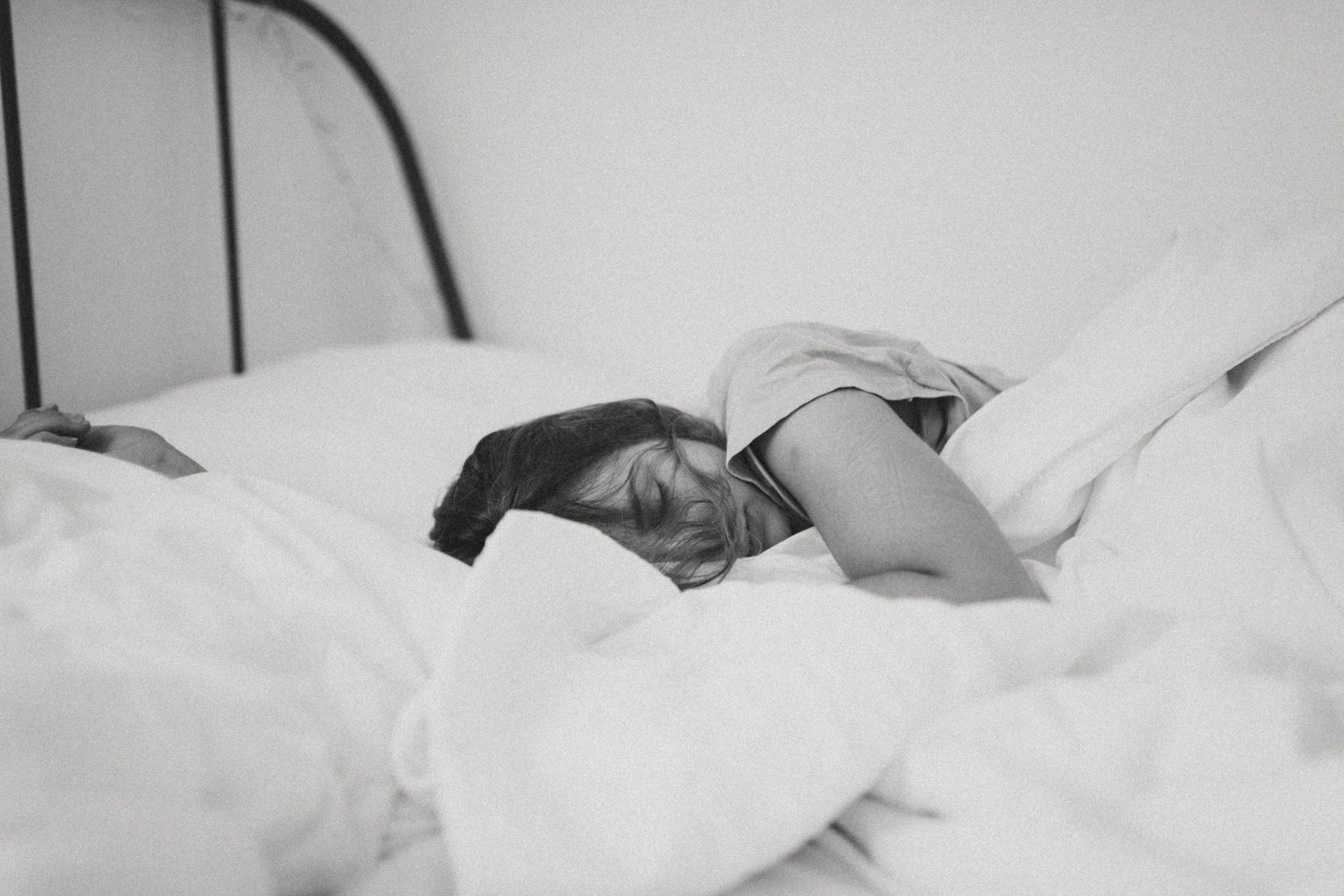 grayscale photo of sleeping woman lying on bed photo