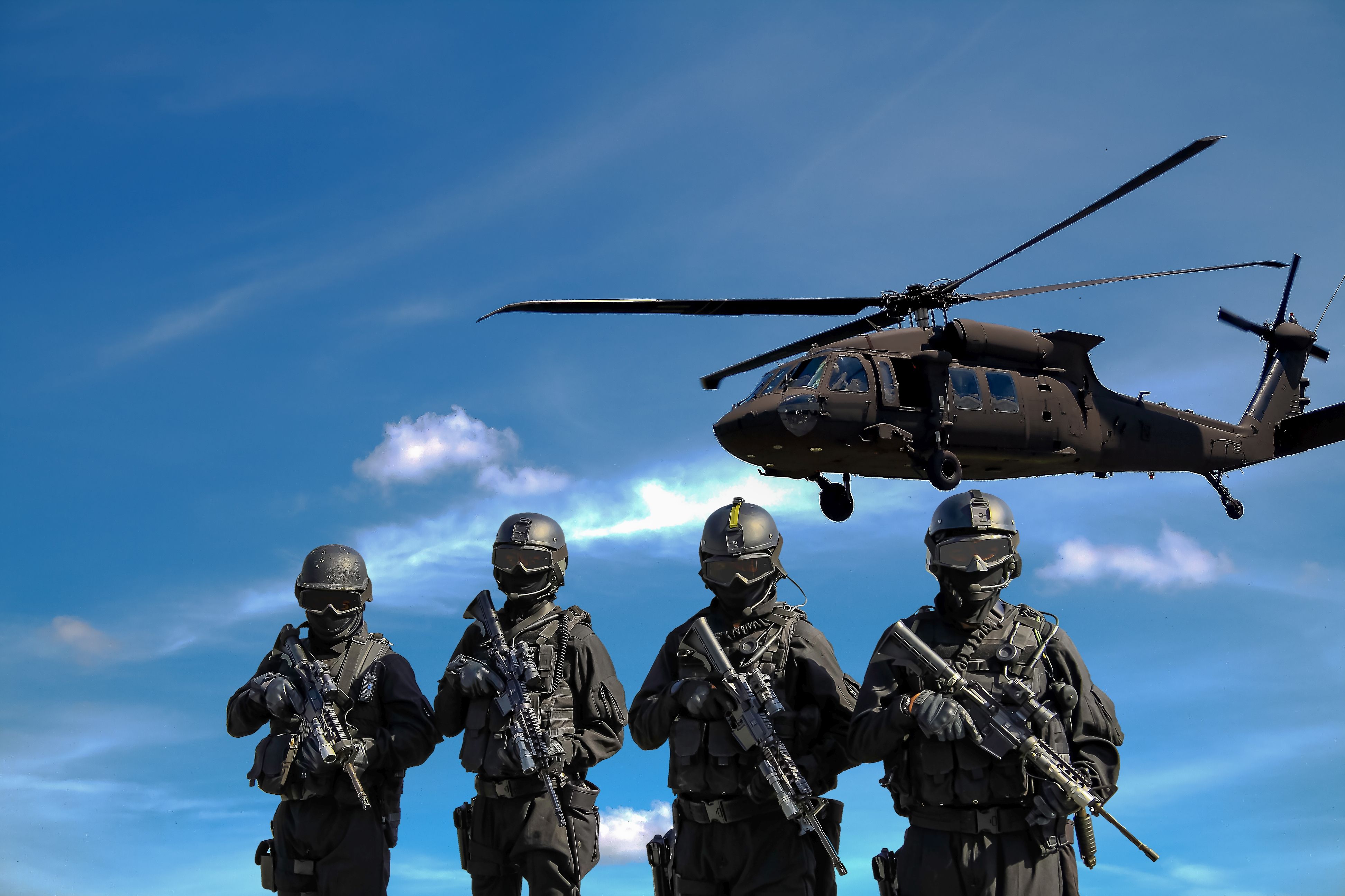Four Soldiers Carrying Rifles Near Helicopter Under Blue Sky · Free