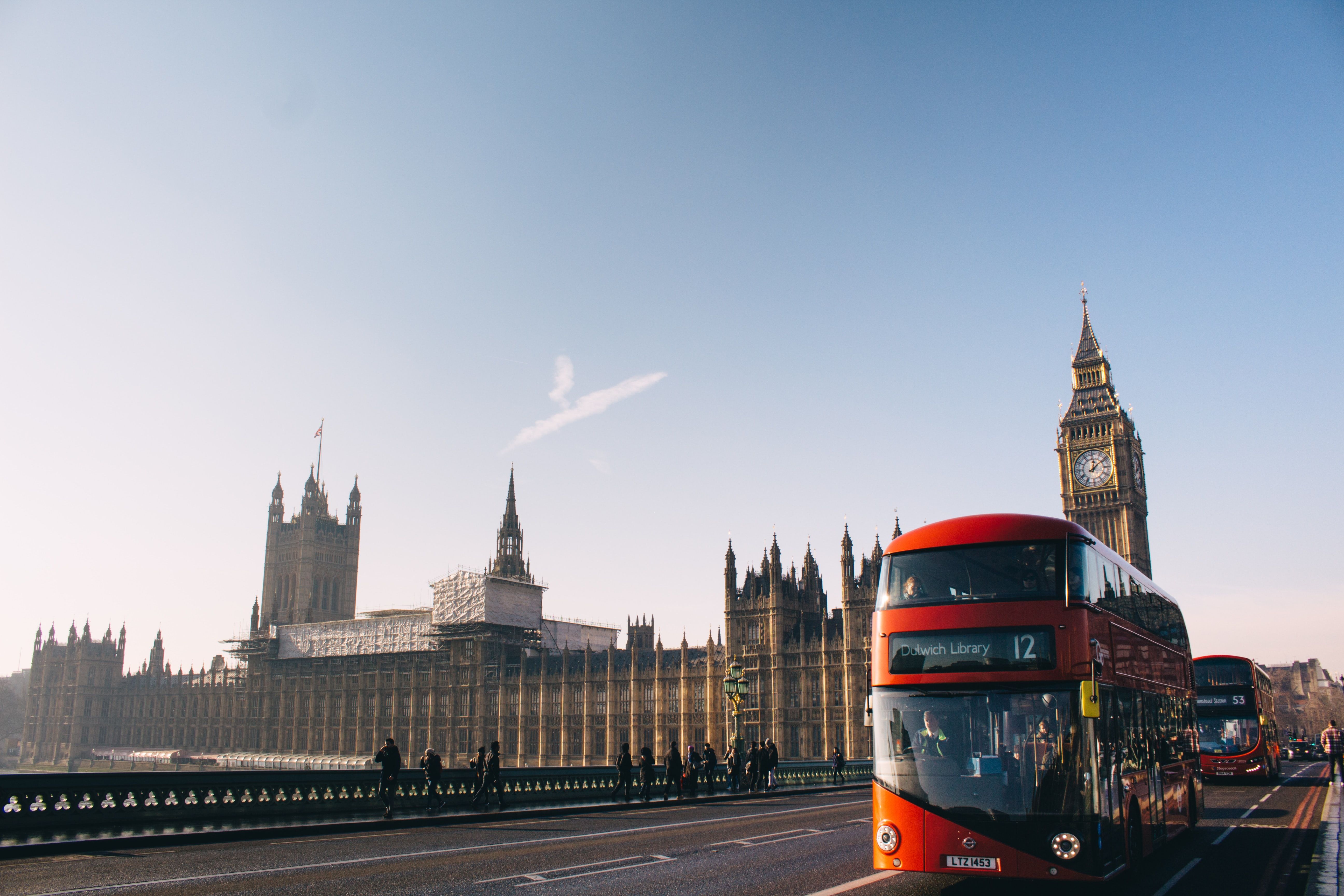 Red Double Decker Bus Passing Palace Of Westminster, London During Daytime Photo