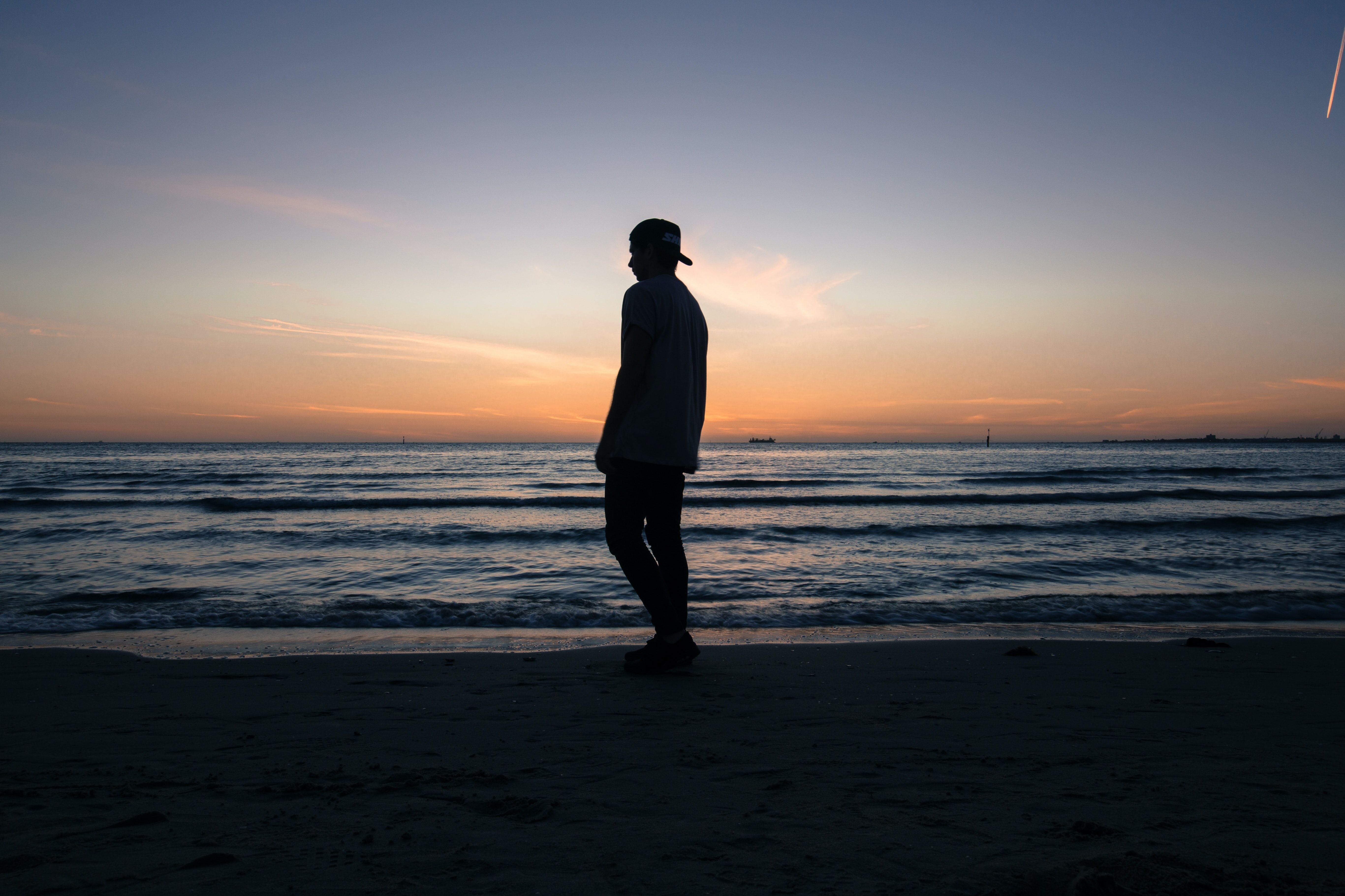 man standing on beach shore during daytime photo