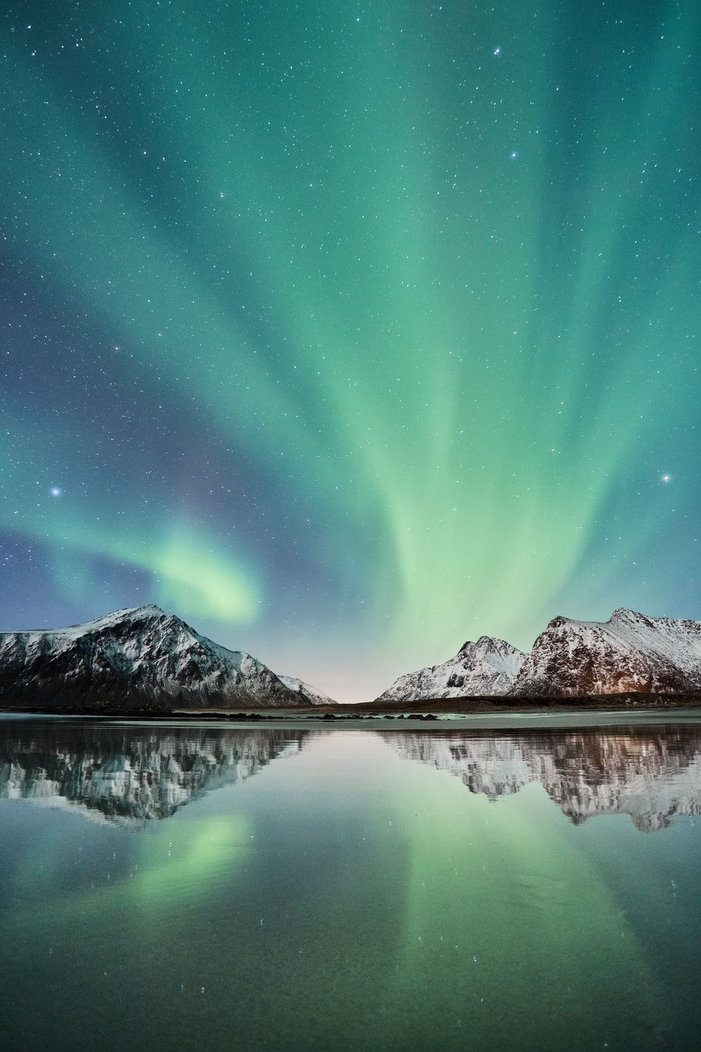 Northern Lights Over Snow Capped Mountian Photo