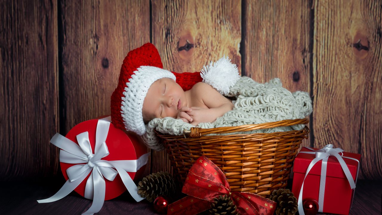 A small baby is sleeping in a wicker basket with Christmas gifts Desktop wallpaper 1280x720