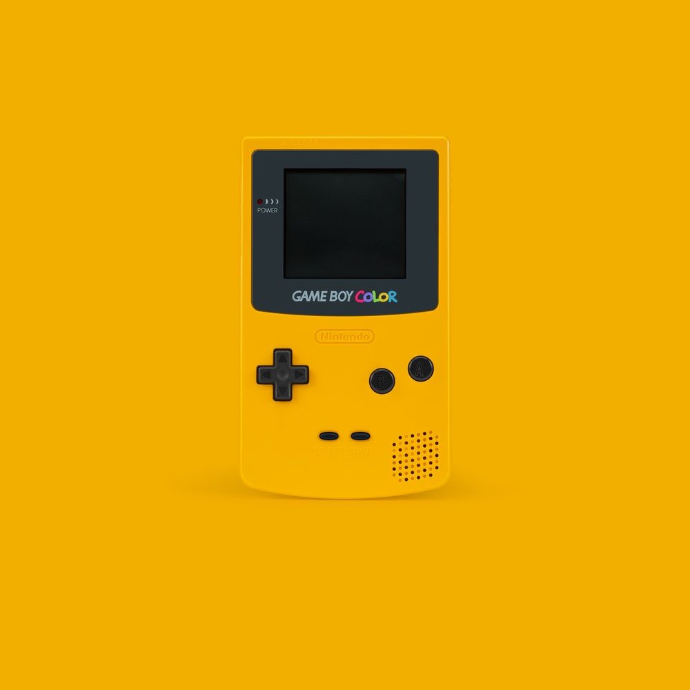 white and black Nintendo Game Boy Color on yellow surface photo